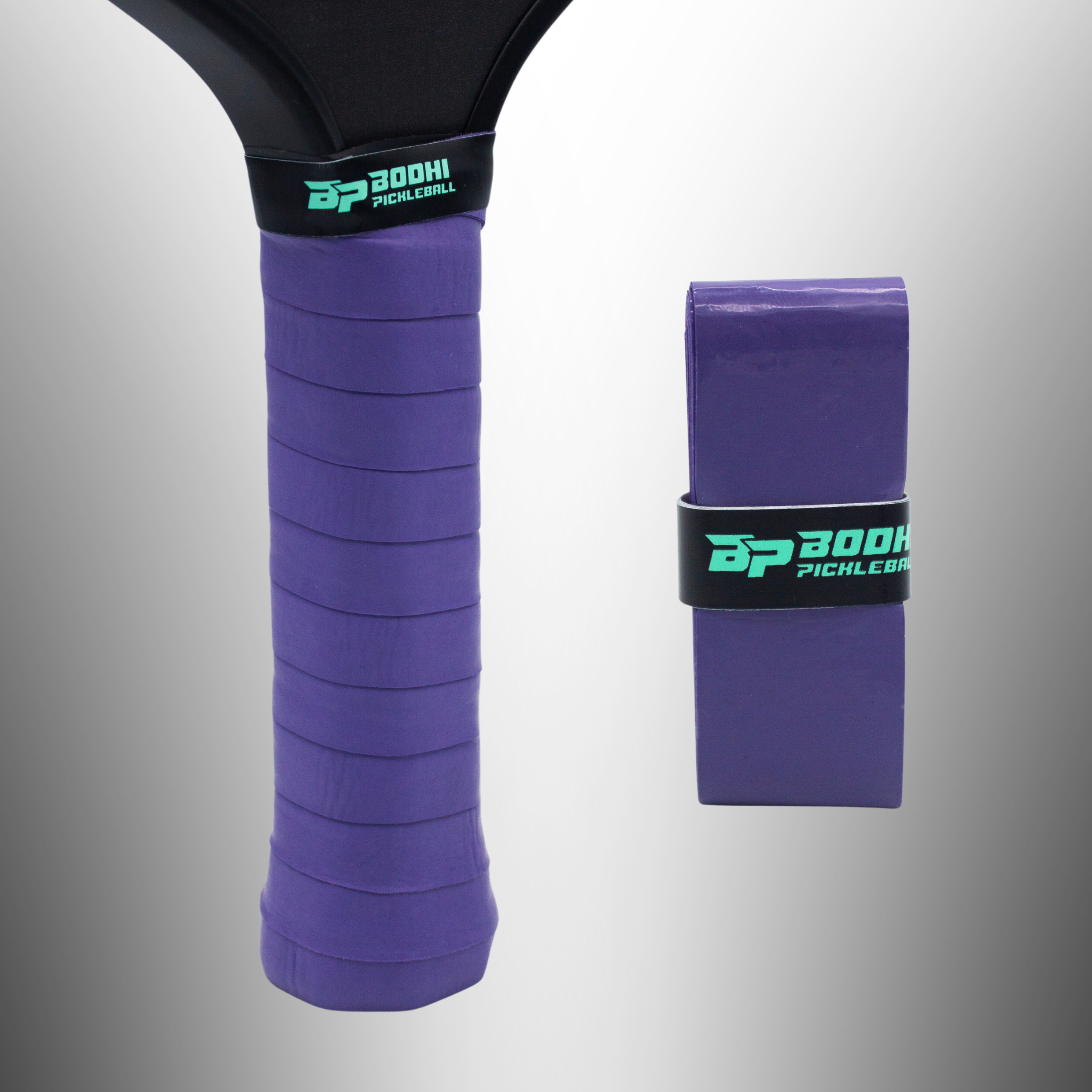 Purple pickleball overgrip by Bodhi Pickleball, wrapped on a black paddle handle alongside a new rolled overgrip.