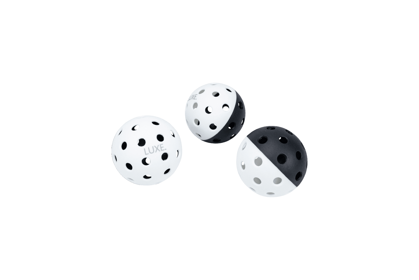 Three pickleball balls with holes: one white, one black and white, one white and black.