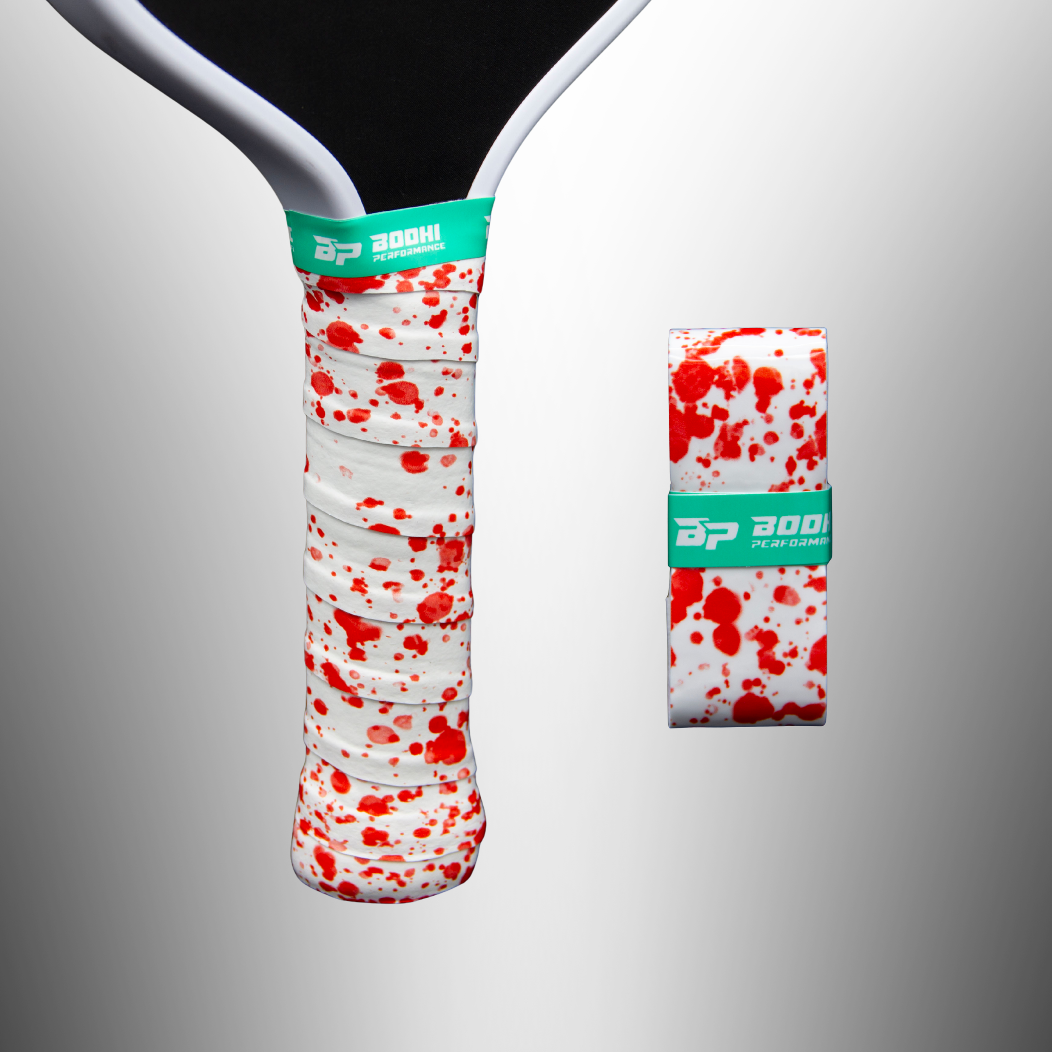 White and red splatter custom overgrips by Bodhi Performance, one wrapped on a paddle, another rolled up, both with green logo bands.