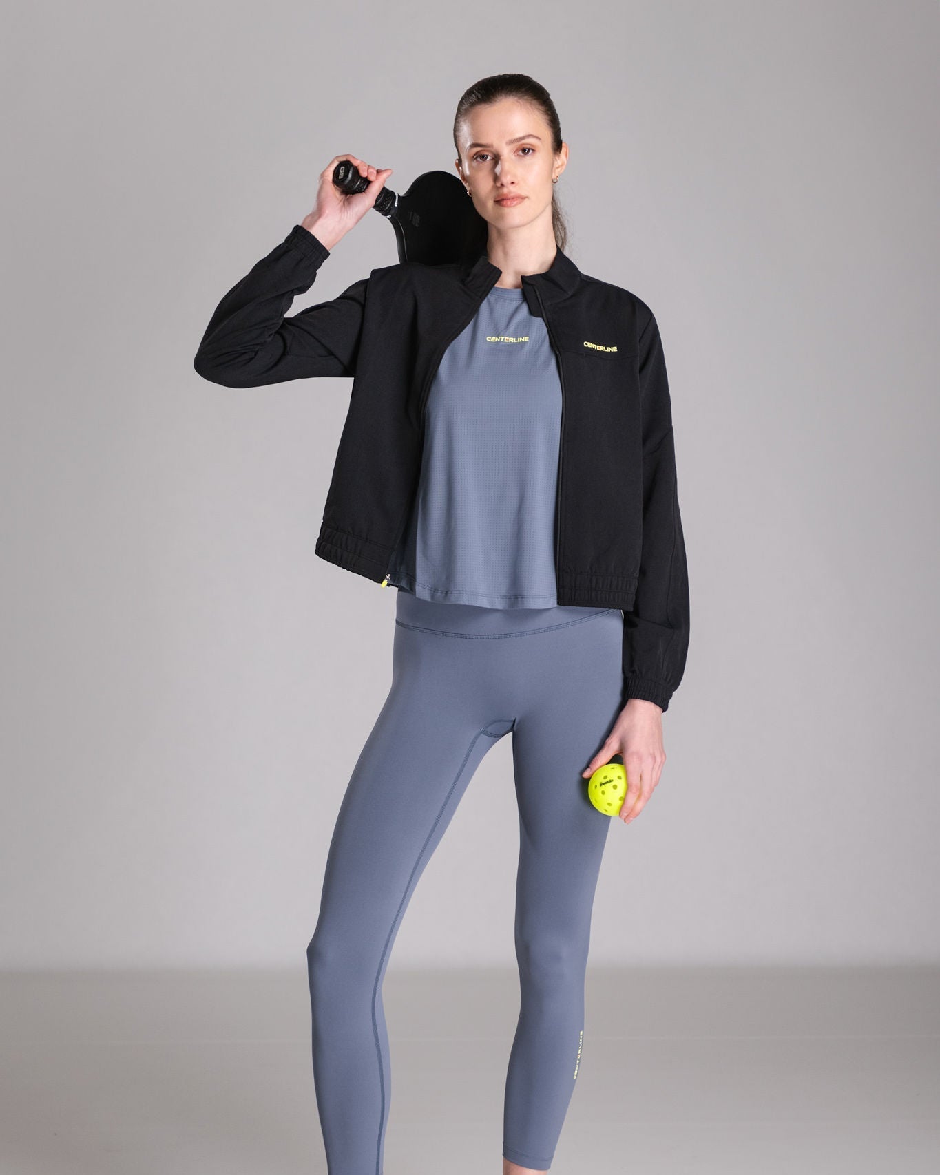 Woman in activewear holding a pickleball paddle and ball.