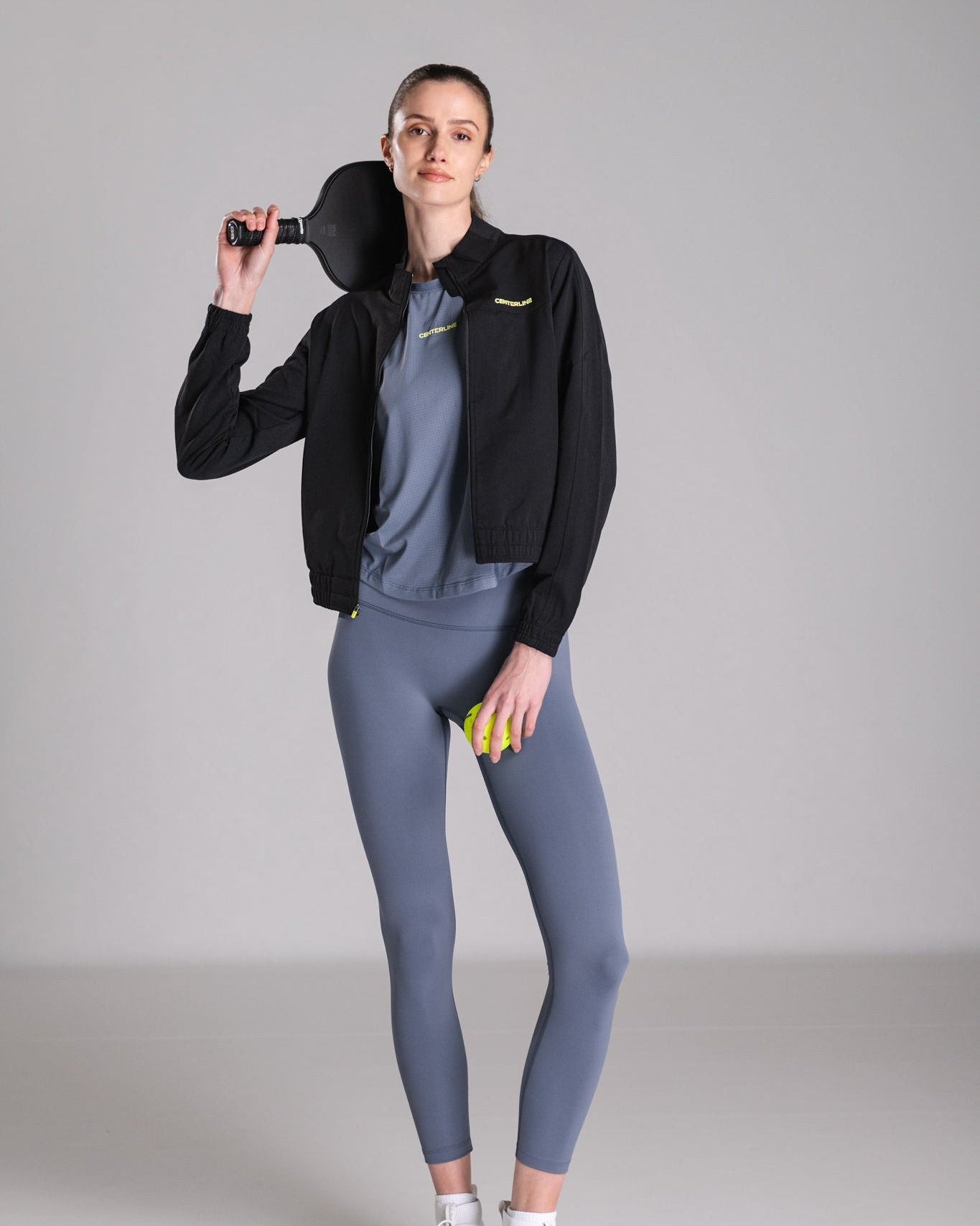 Woman in sportswear with pickleball paddle and ball.