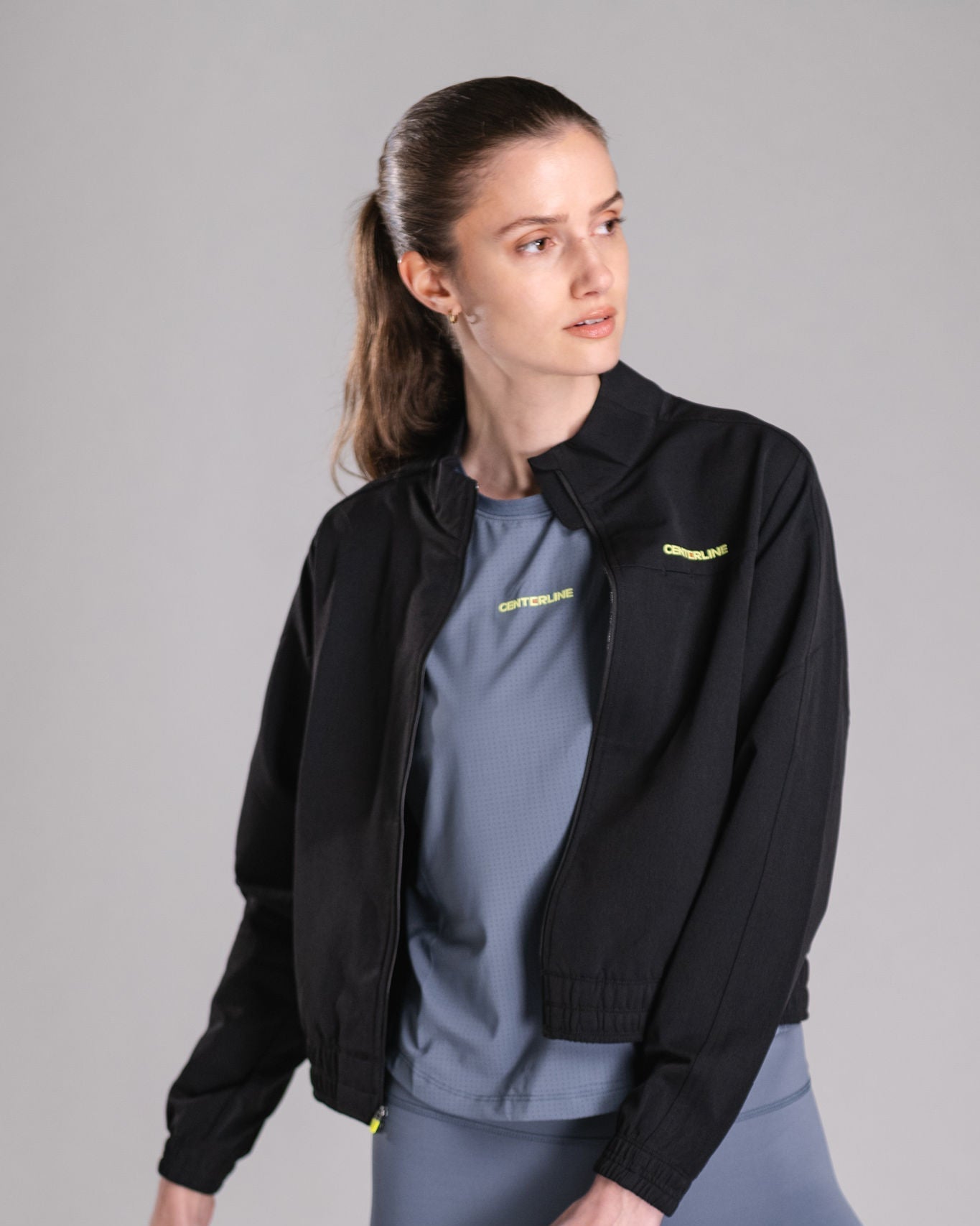 Woman in black zip-up jacket and gray athletic shirt.