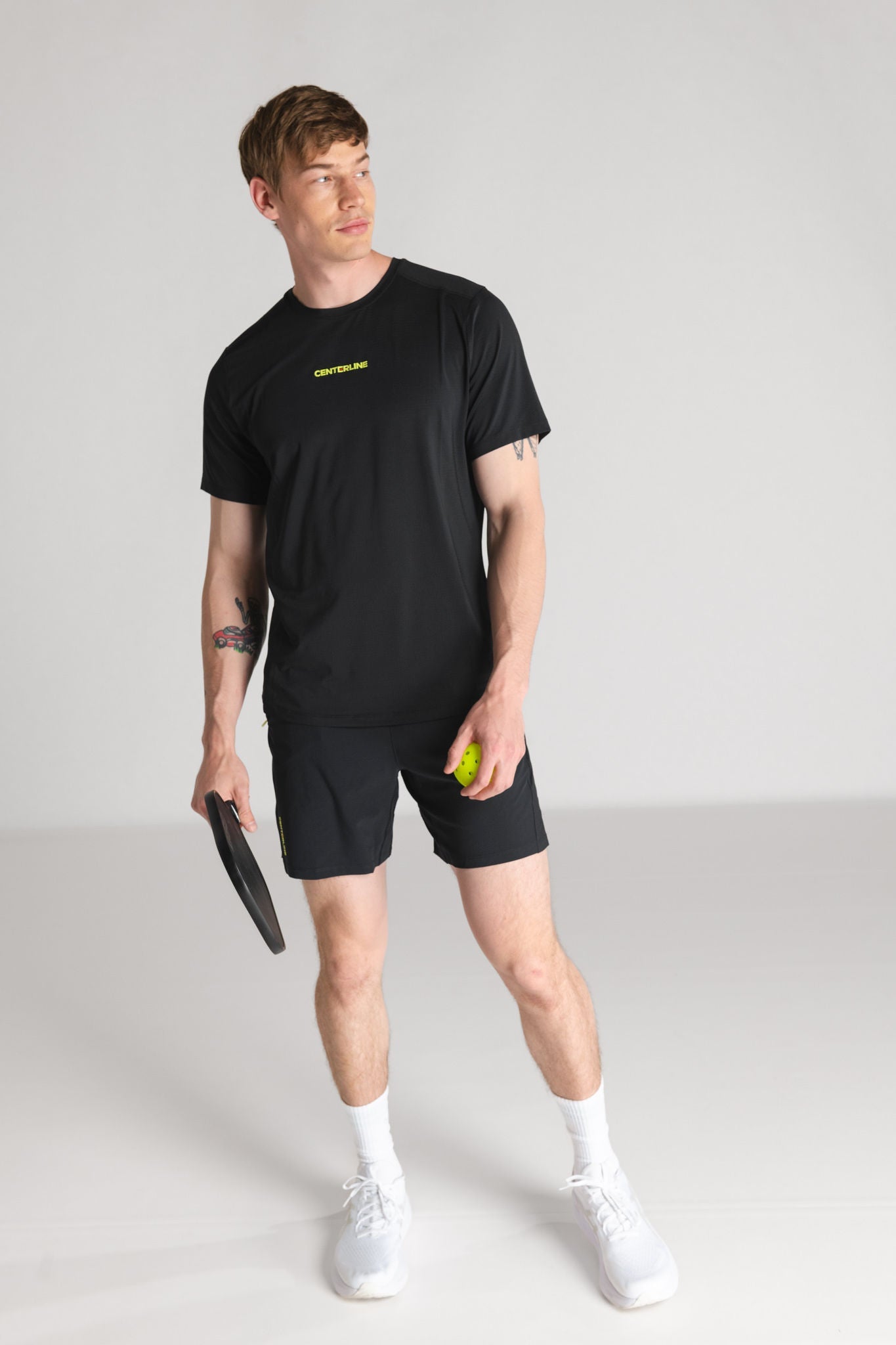Man in athletic wear with pickleball paddle and ball.