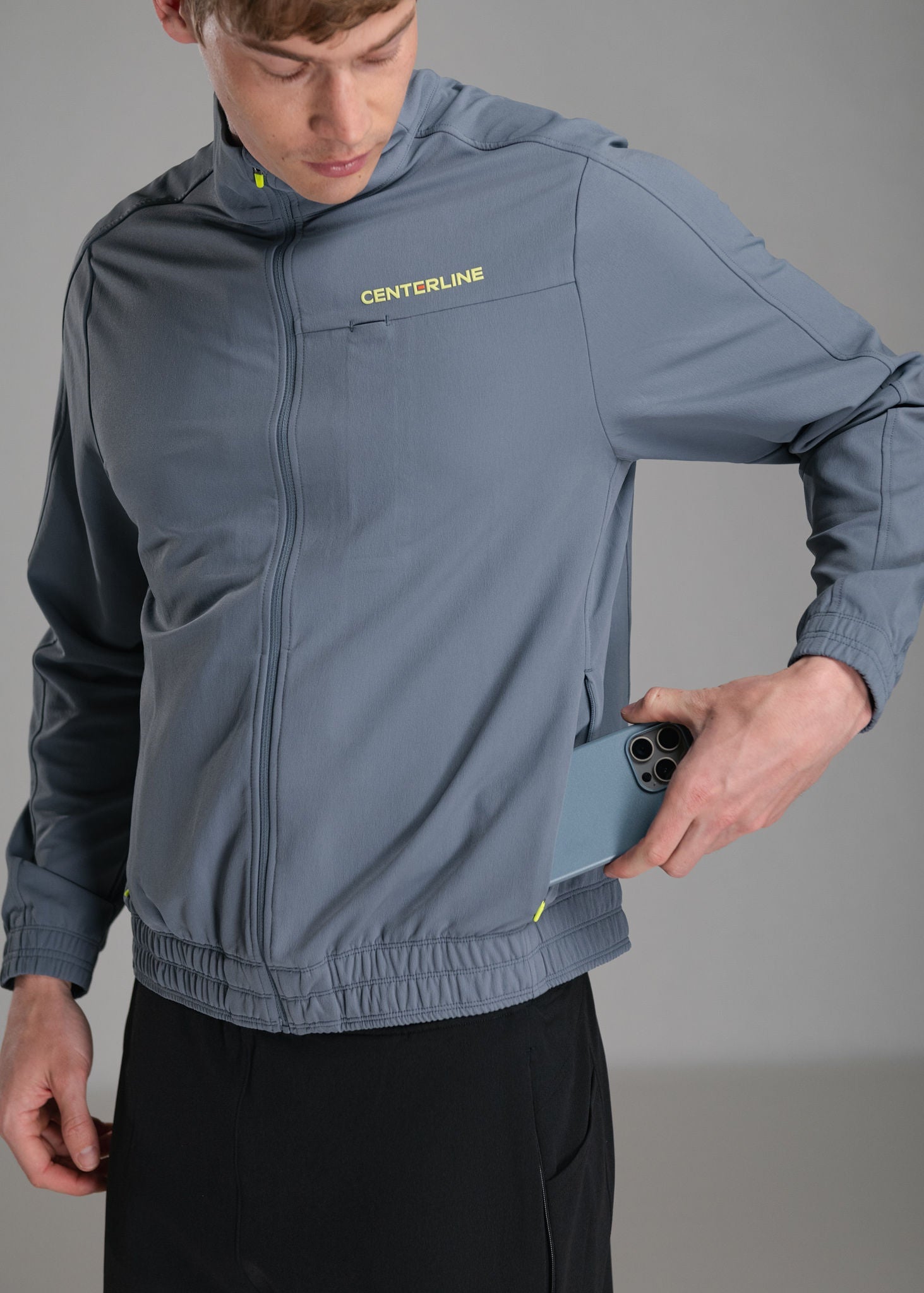 Man in gray jacket with phone in pocket.