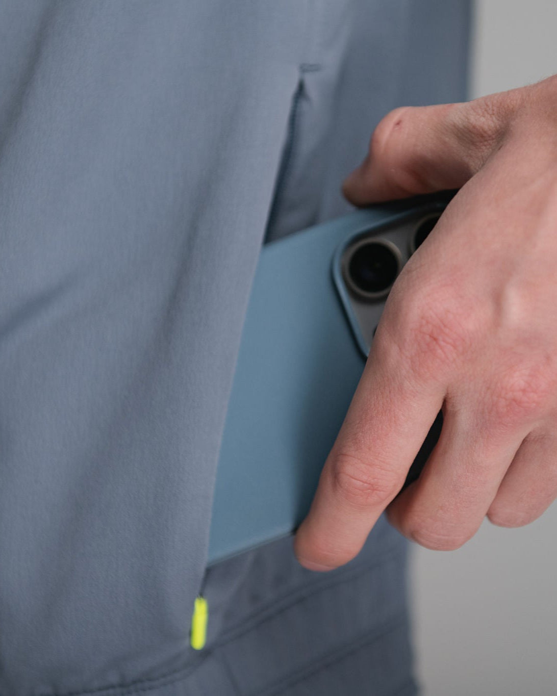 Person puts blue phone in blue pants pocket.