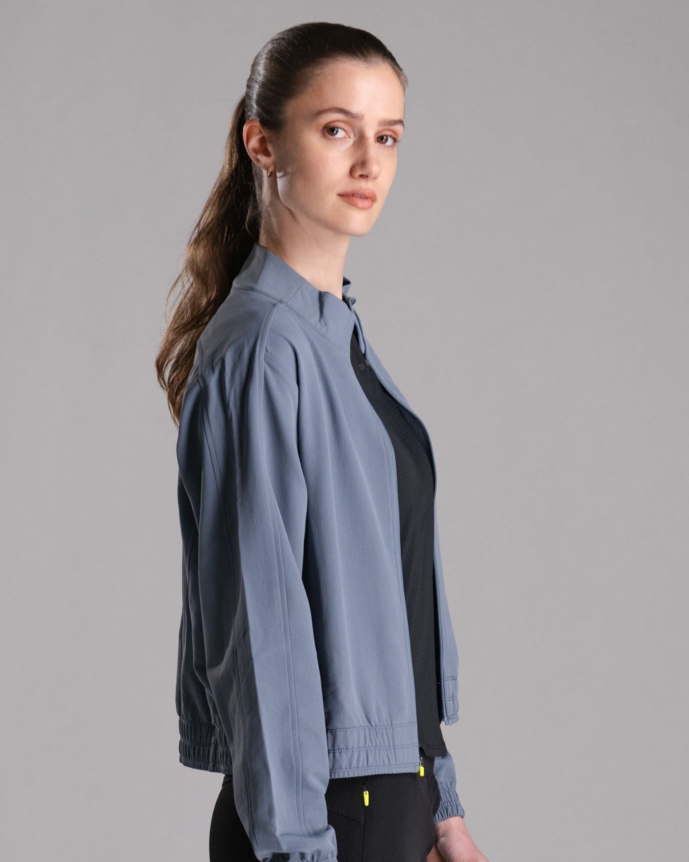A woman in a blue bomber jacket over a black top.