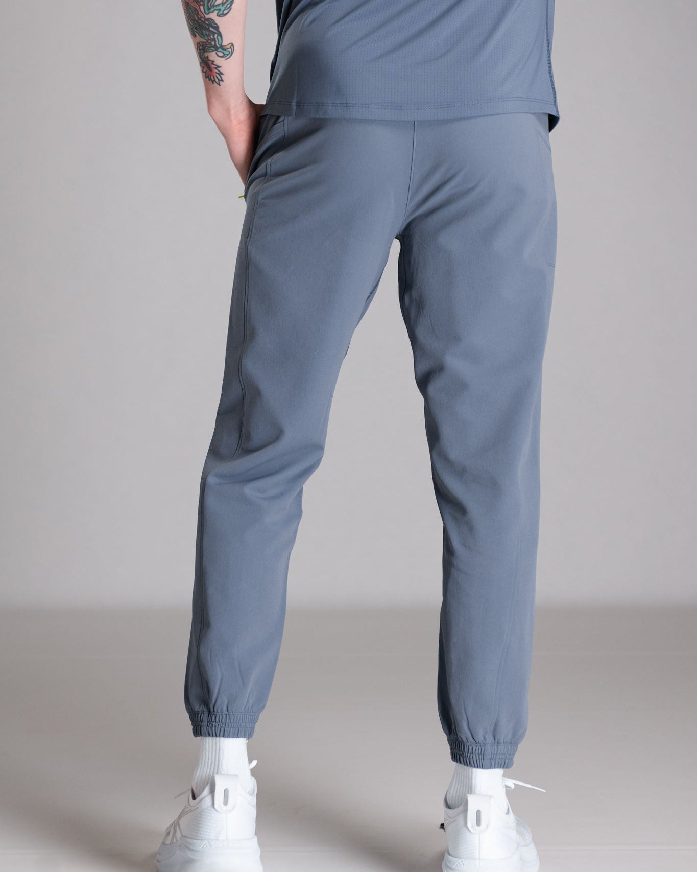A person wearing blue track pants, white socks, and sneakers.