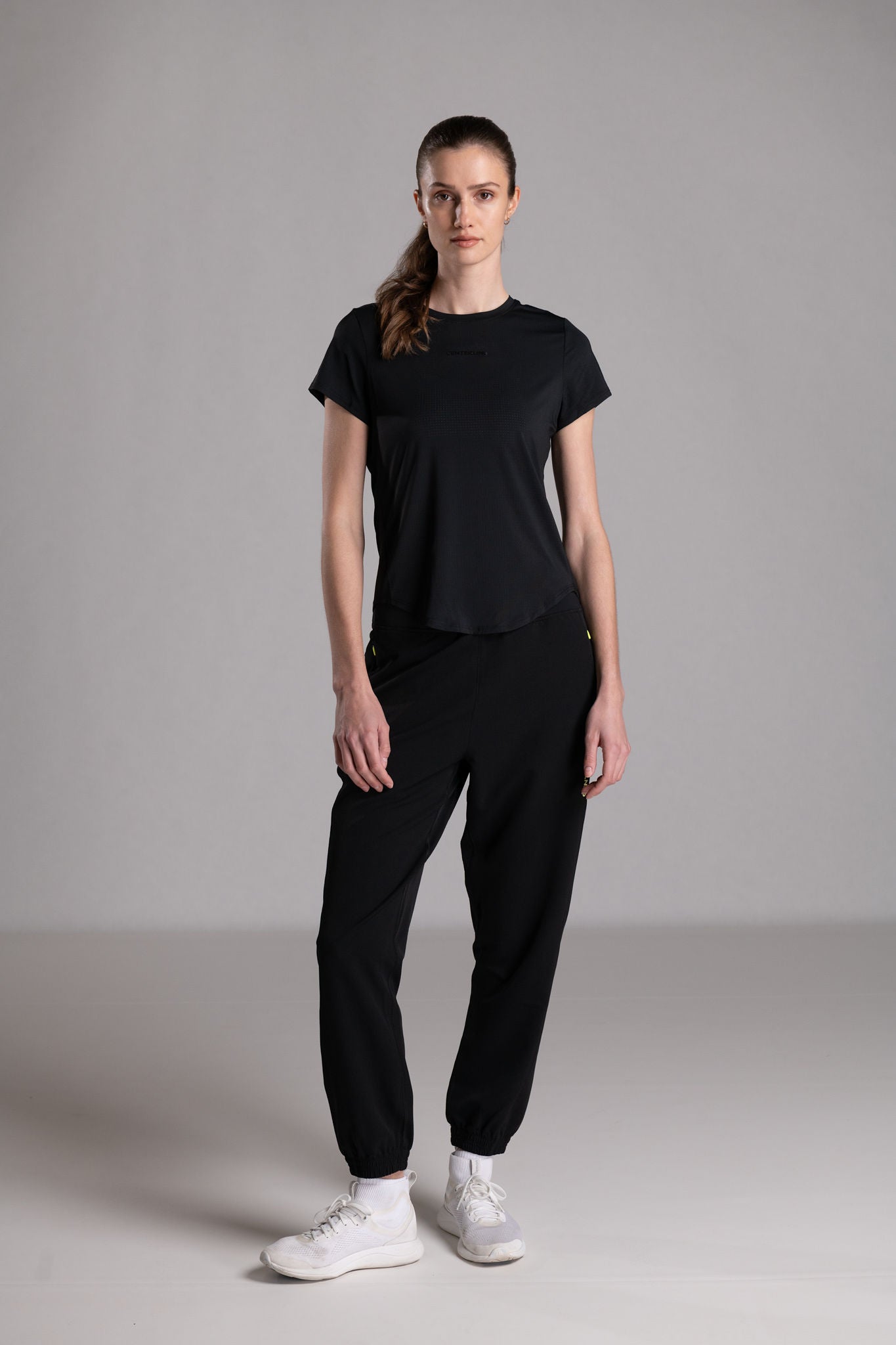 Woman wearing black athleisure set with white sneakers.