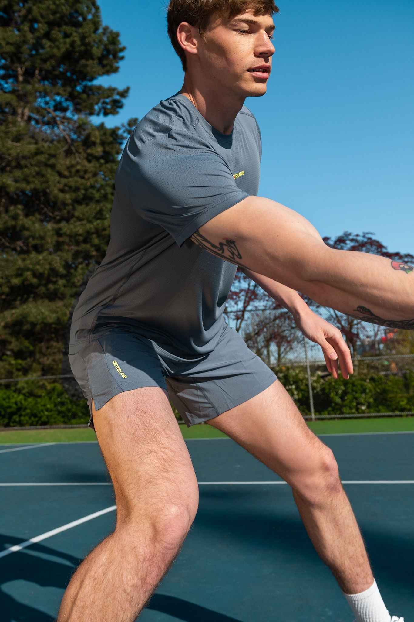 Man playing tennis in a gray t-shirt and shorts.