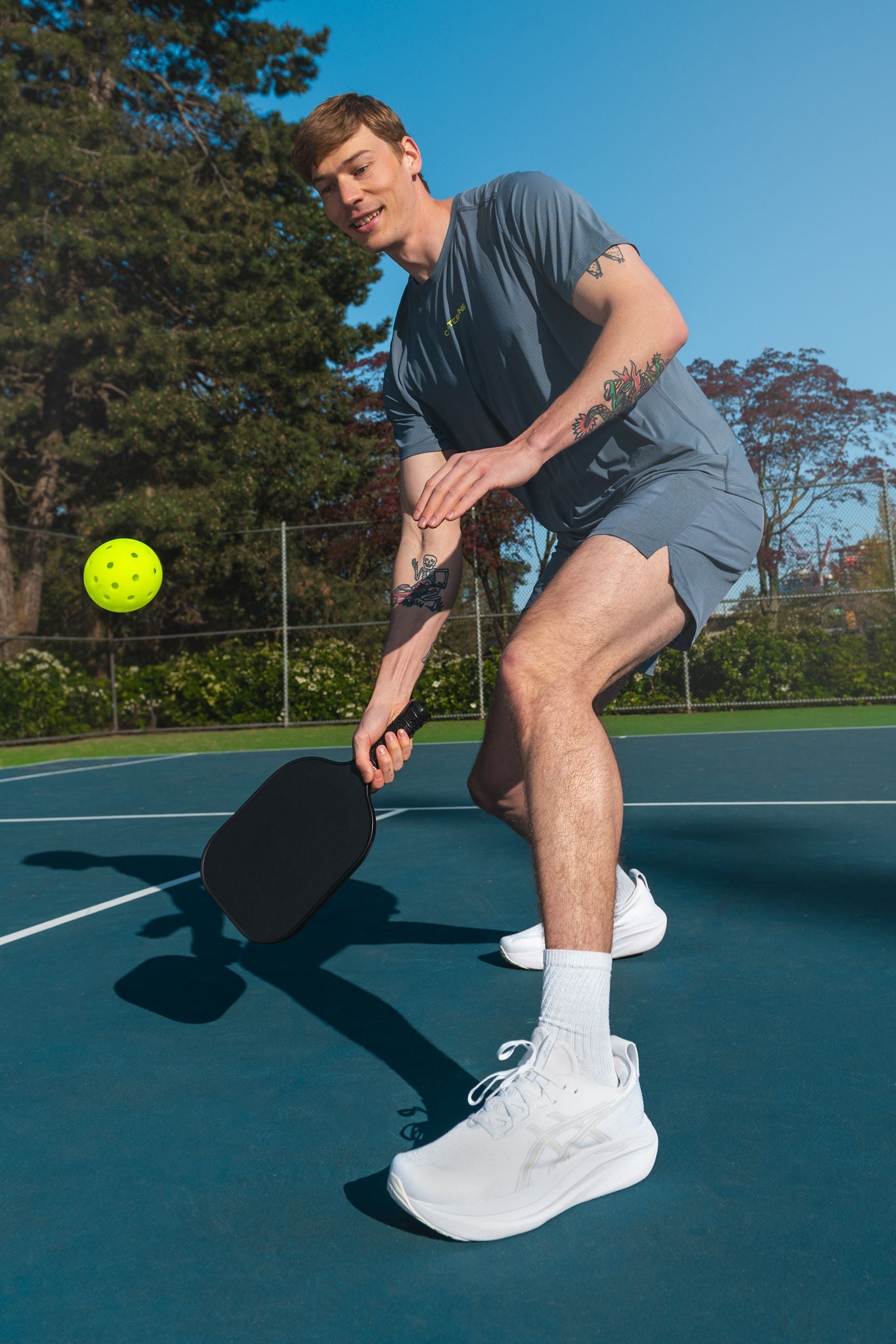 Man playing pickleball wearing activewear and white sneakers.