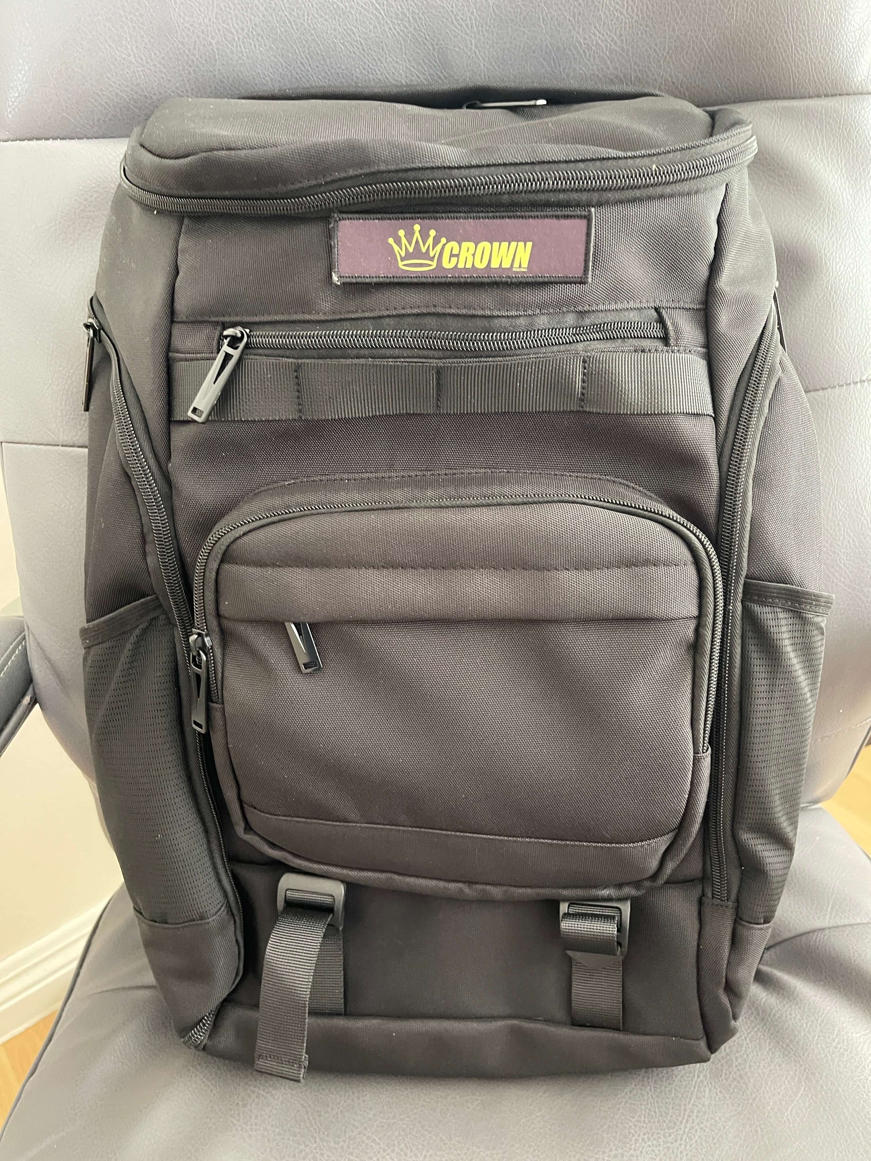 Black backpack with "Crown" logo on a gray chair.