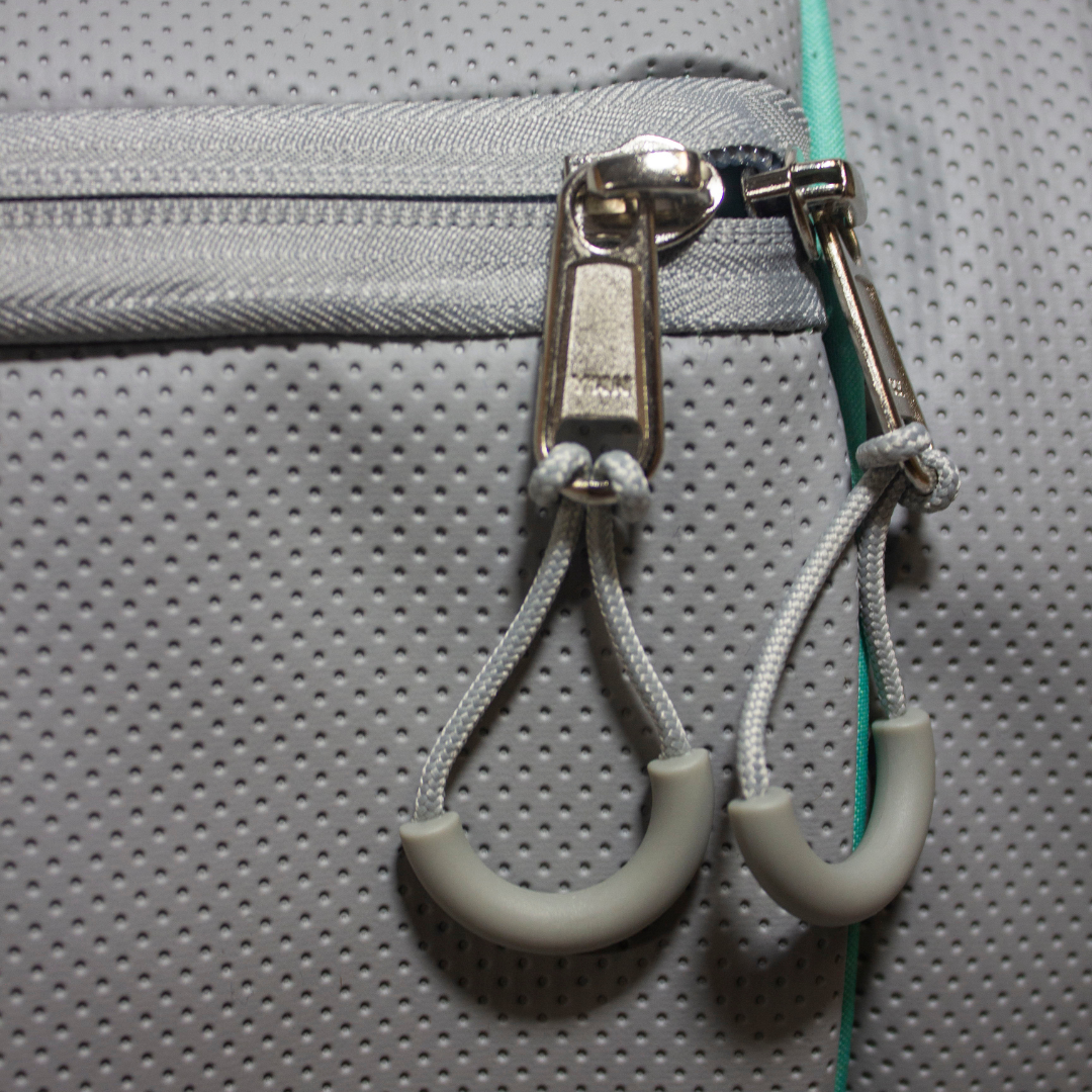 Grey perforated duffle bag by Bodhi Pickleball featuring silver YKK zippers with grey cord and U-shaped rubber grips.