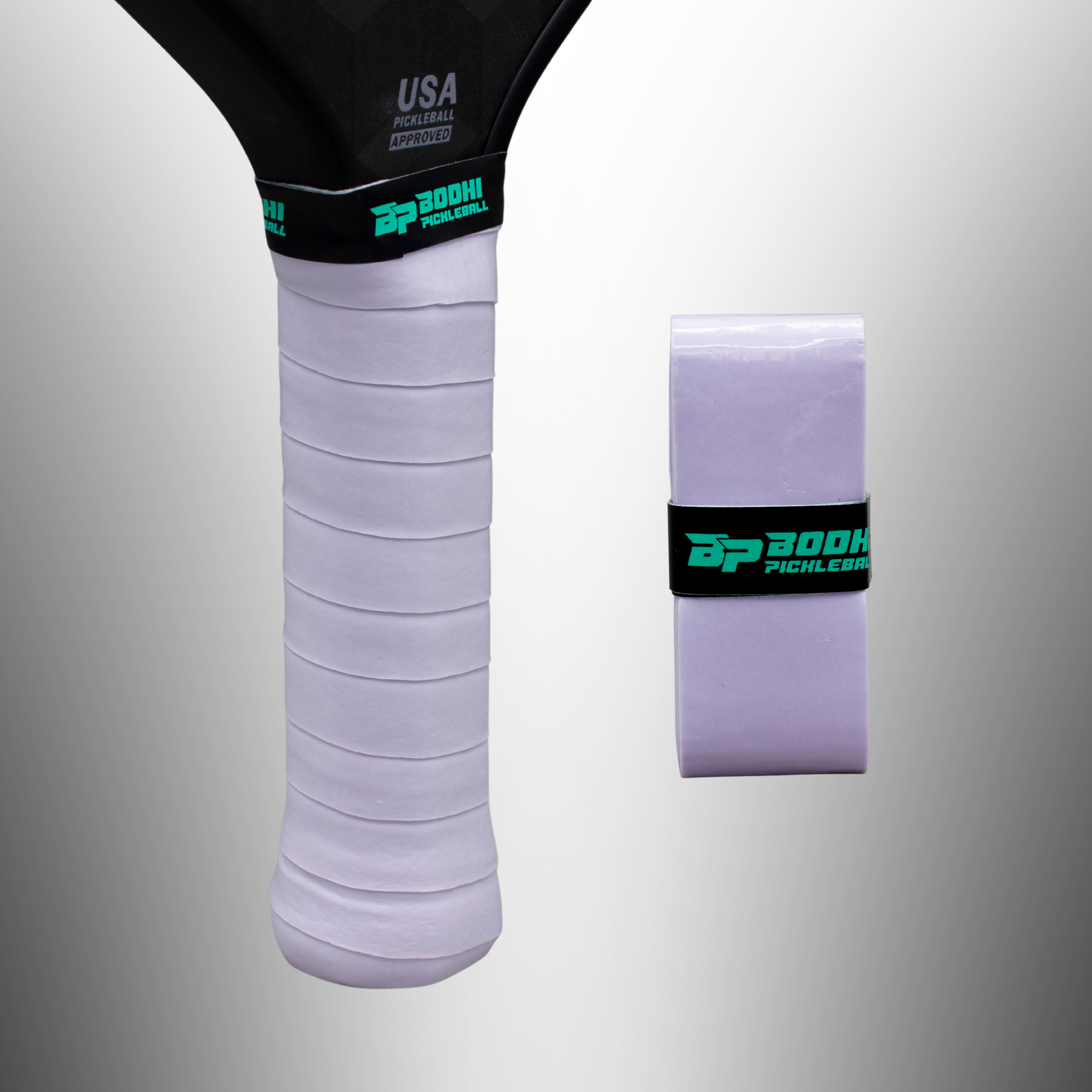 Light purple pickleball paddle overgrips by Bodhi Pickleball, one wrapped on a black paddle handle, another rolled beside it.
