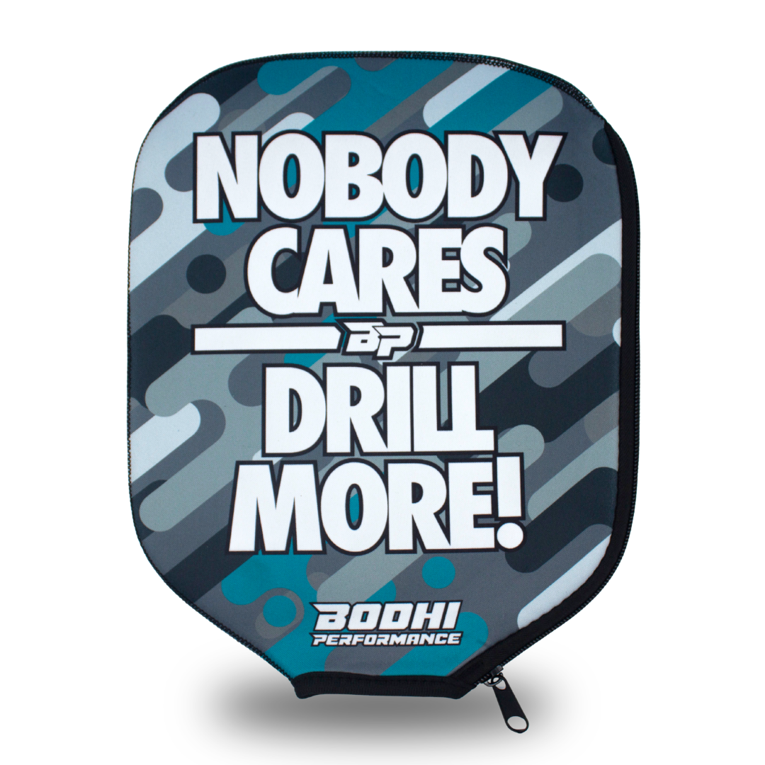 Padded paddle cover by Bodhi Performance, with teal, light blue, and gray camouflage pattern and "NOBODY CARES DRILL MORE!" text.
