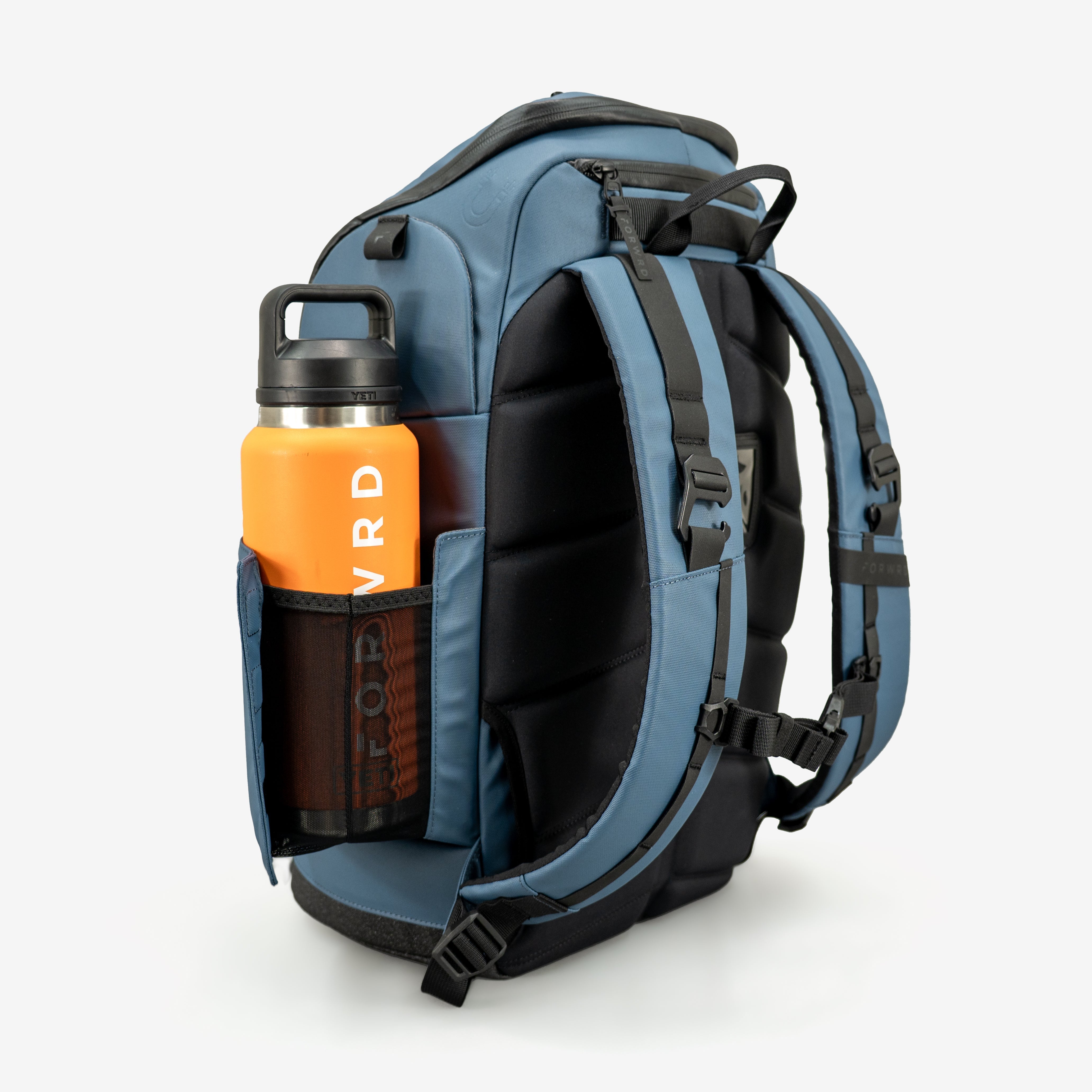 Blue pickleball backpack by FORWRD, shown from the side with an orange water bottle in a mesh pocket and padded black straps.