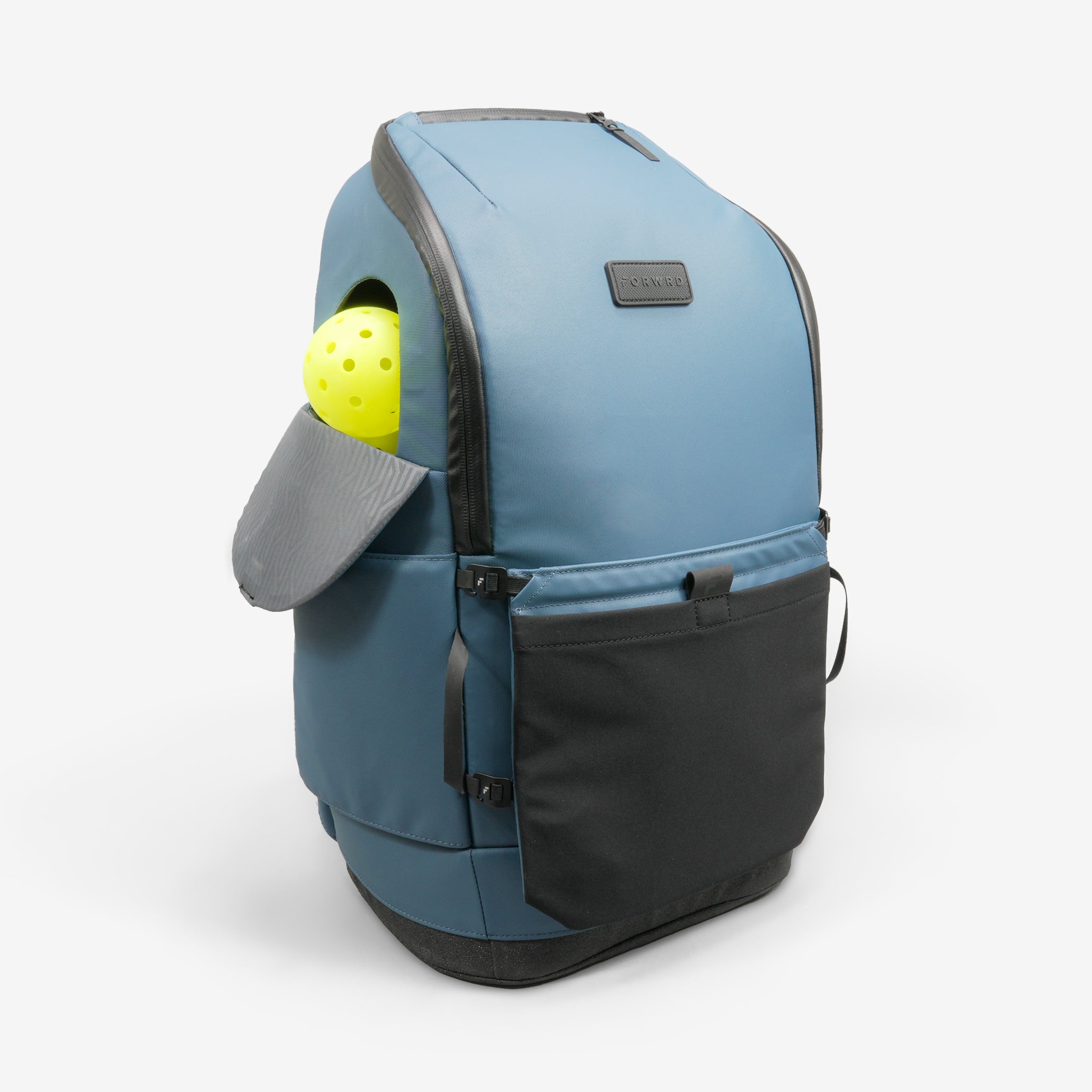 Blue Court Caddy Pickleball Bag by FORWRD, angled view, with a textured grey side pocket holding a yellow pickleball, and a black front pocket.