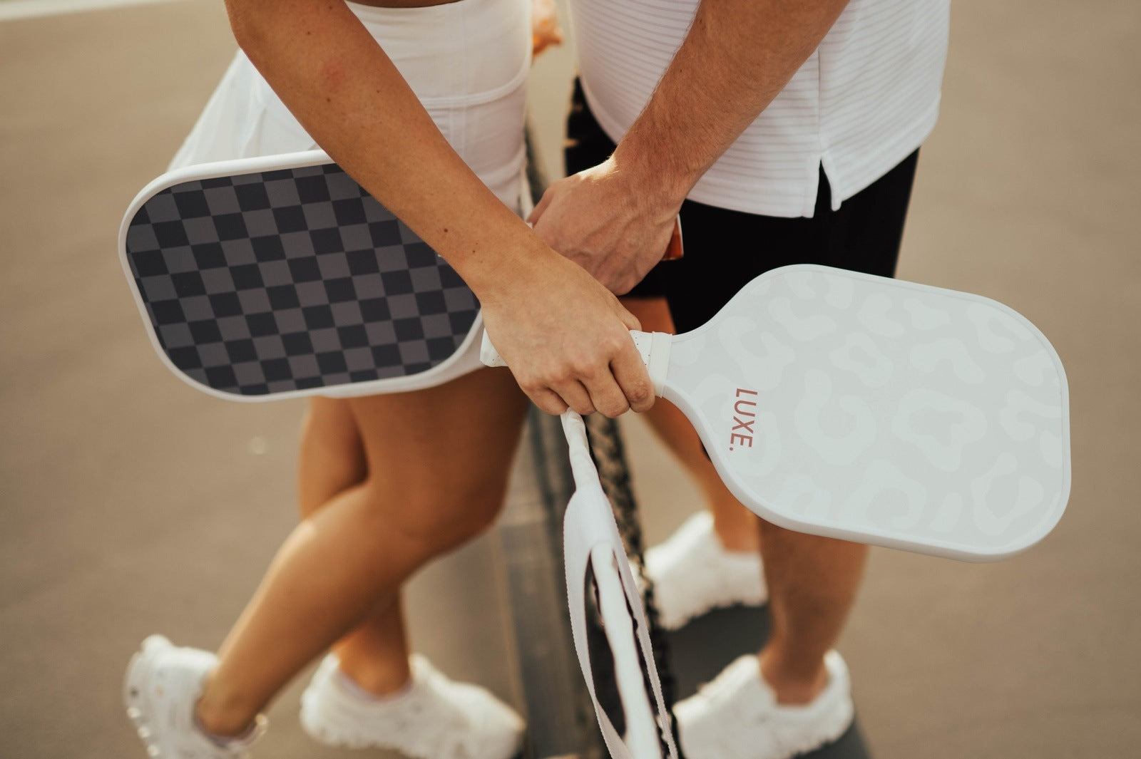 Two people in sportswear holding pickleball paddles.