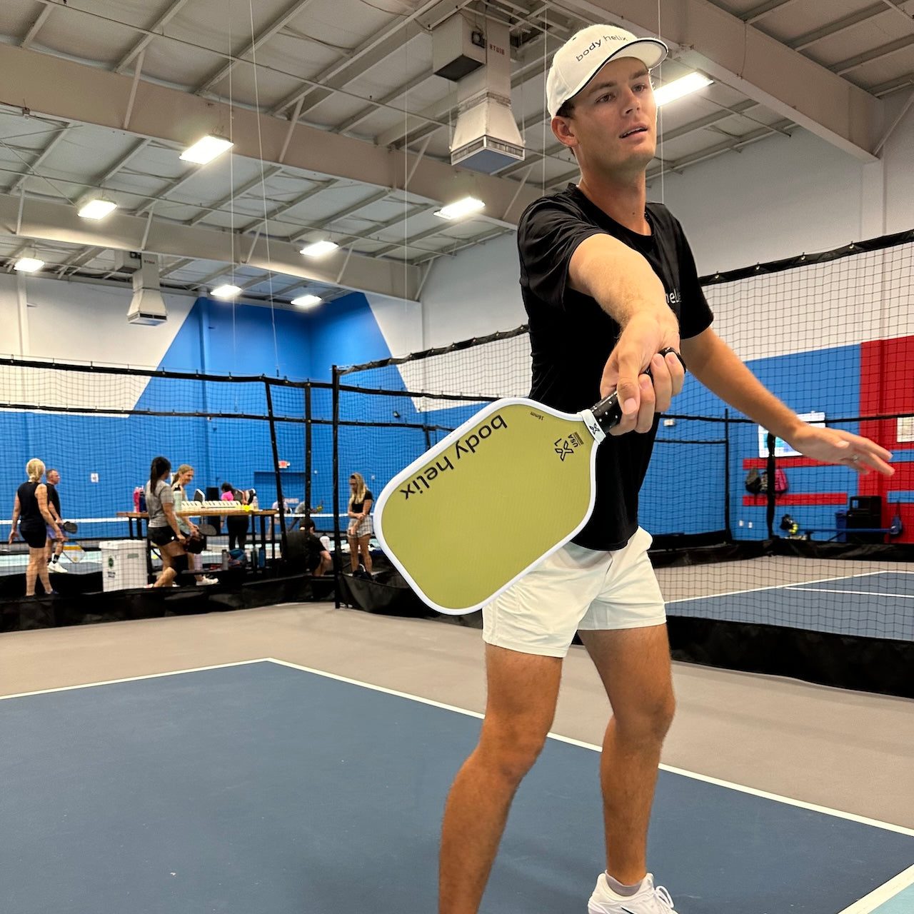 Man in black shirt and white shorts holding a pickleball paddle.