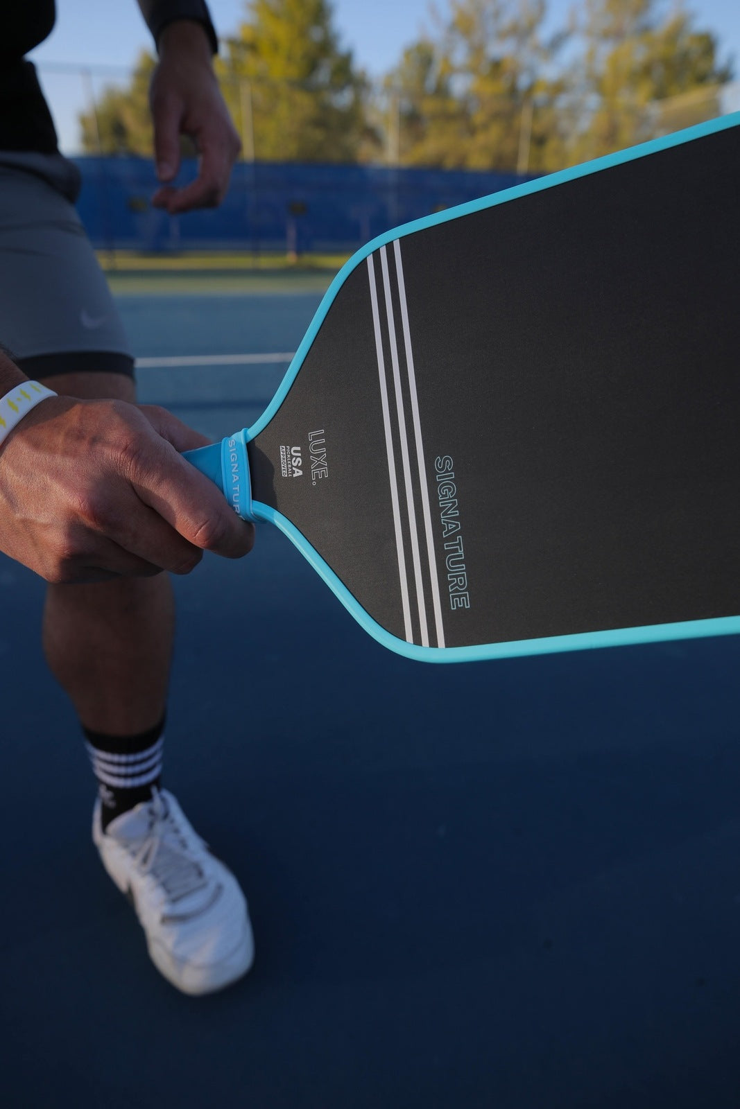 A person holding a black and blue pickleball paddle.