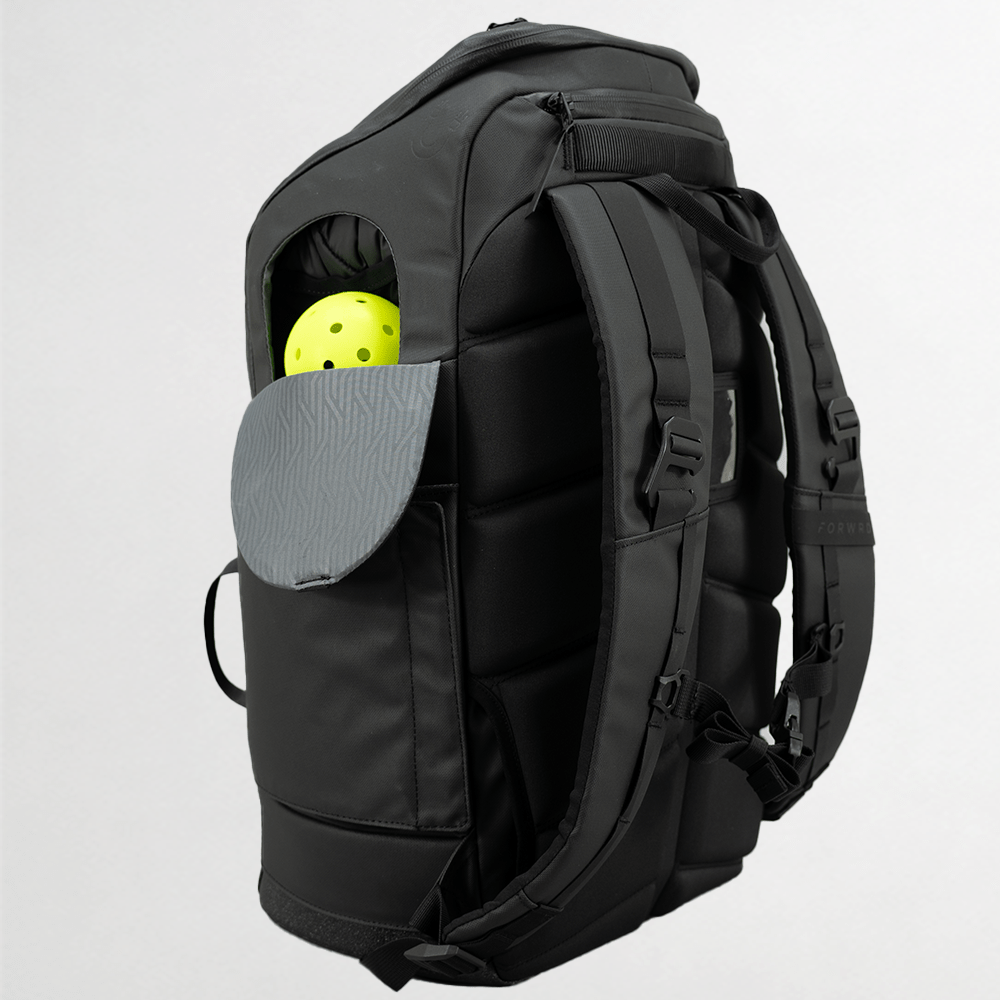 Black pickleball backpack by FORWRD, featuring a side pocket with a gray textured flap and a yellow pickleball, seen from a back-side angle.