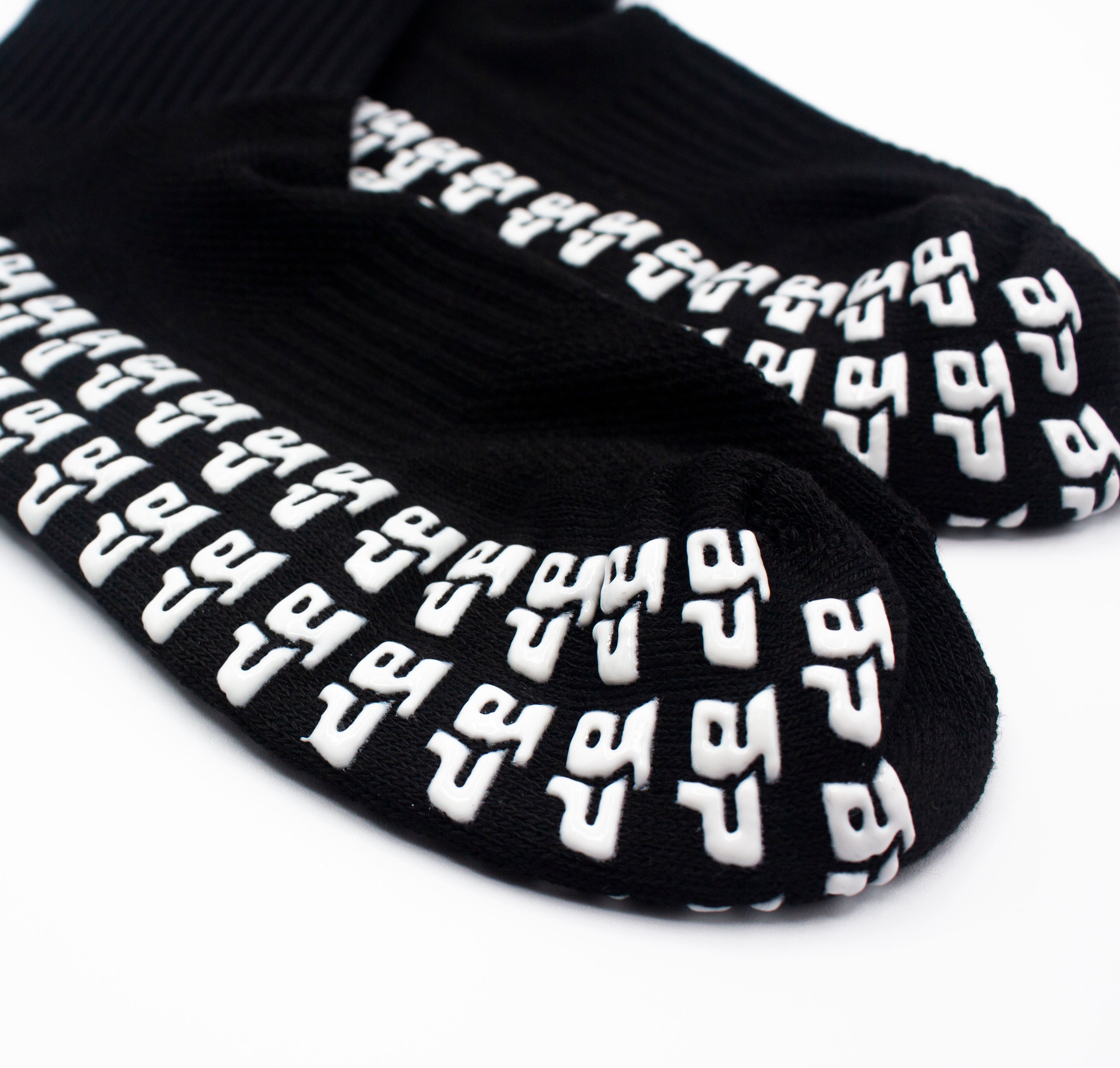 Black performance socks by Bodhi Performance with white textured anti-slip grips on the sole.