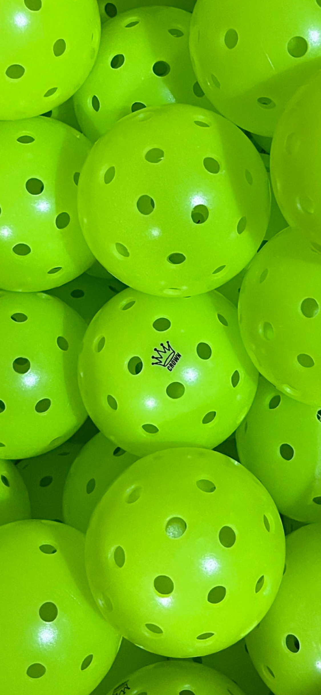 Close-up of neon green pickleballs with holes.
