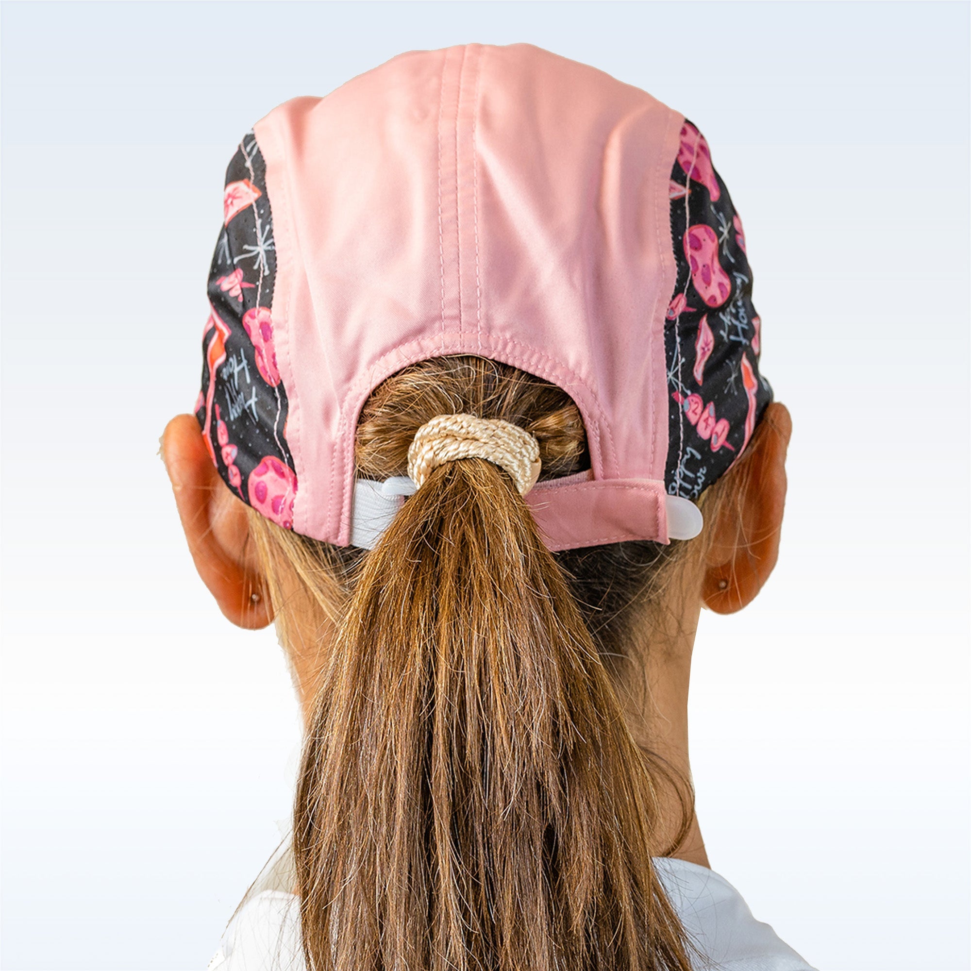 Pink pickleball cap by Pickleball Bella with patterned black side panels featuring martini glasses and "Happy Hour" text, back view.