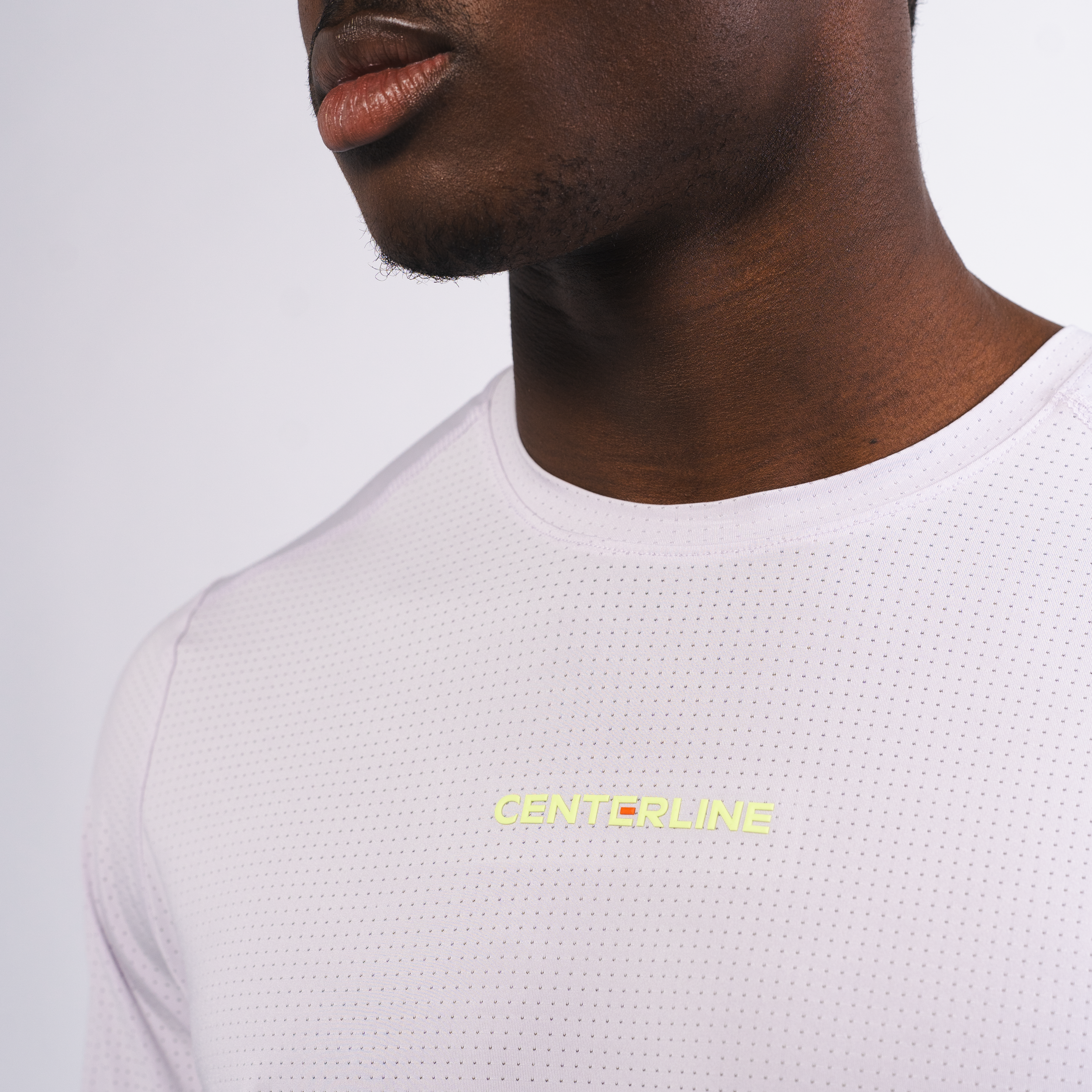 Close-up of a man wearing a light pink mesh shirt with the word "CENTERLINE" printed on the chest in yellow.