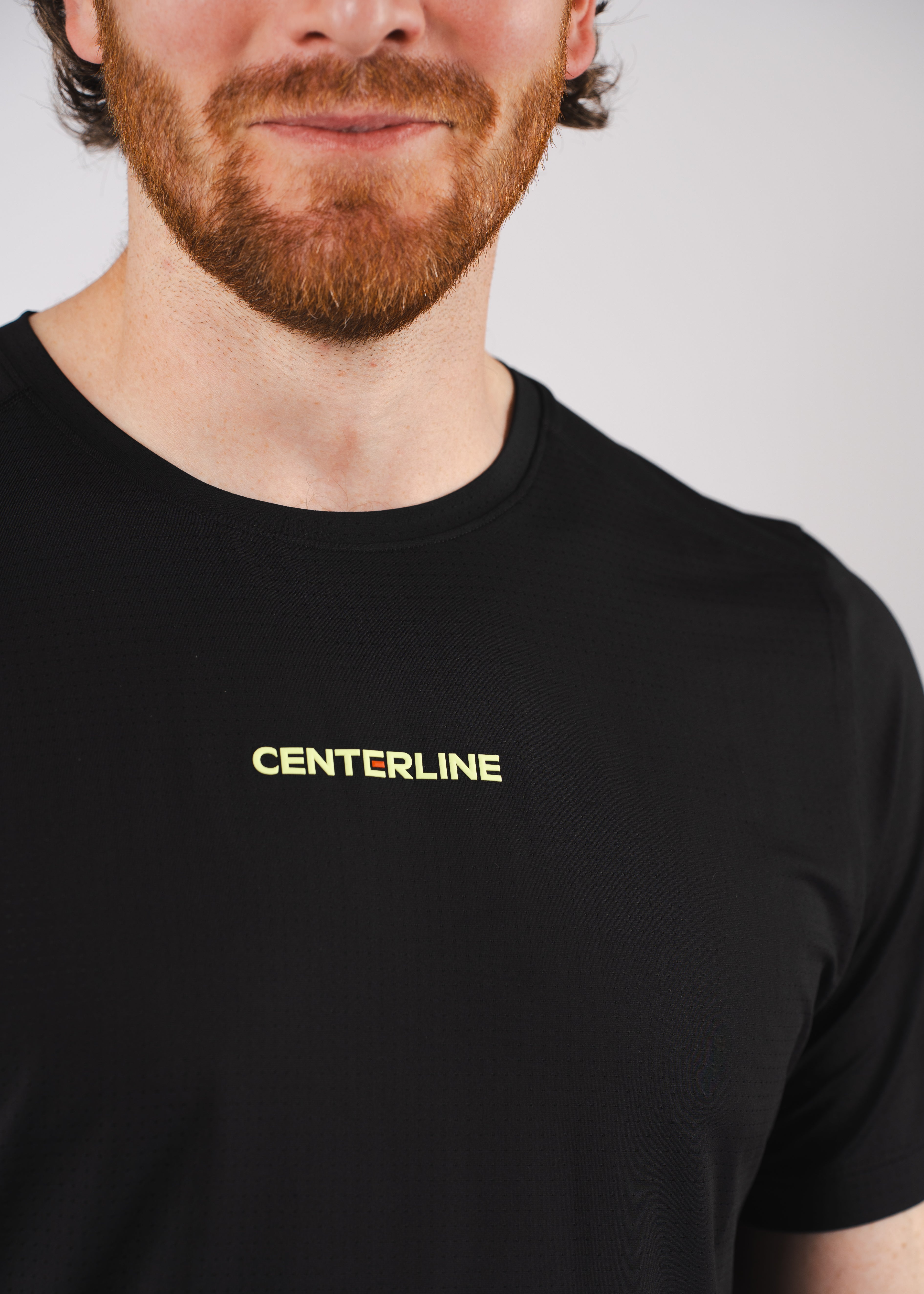 Close-up of a man wearing a black t-shirt with "CENTERLINE" printed in yellow.