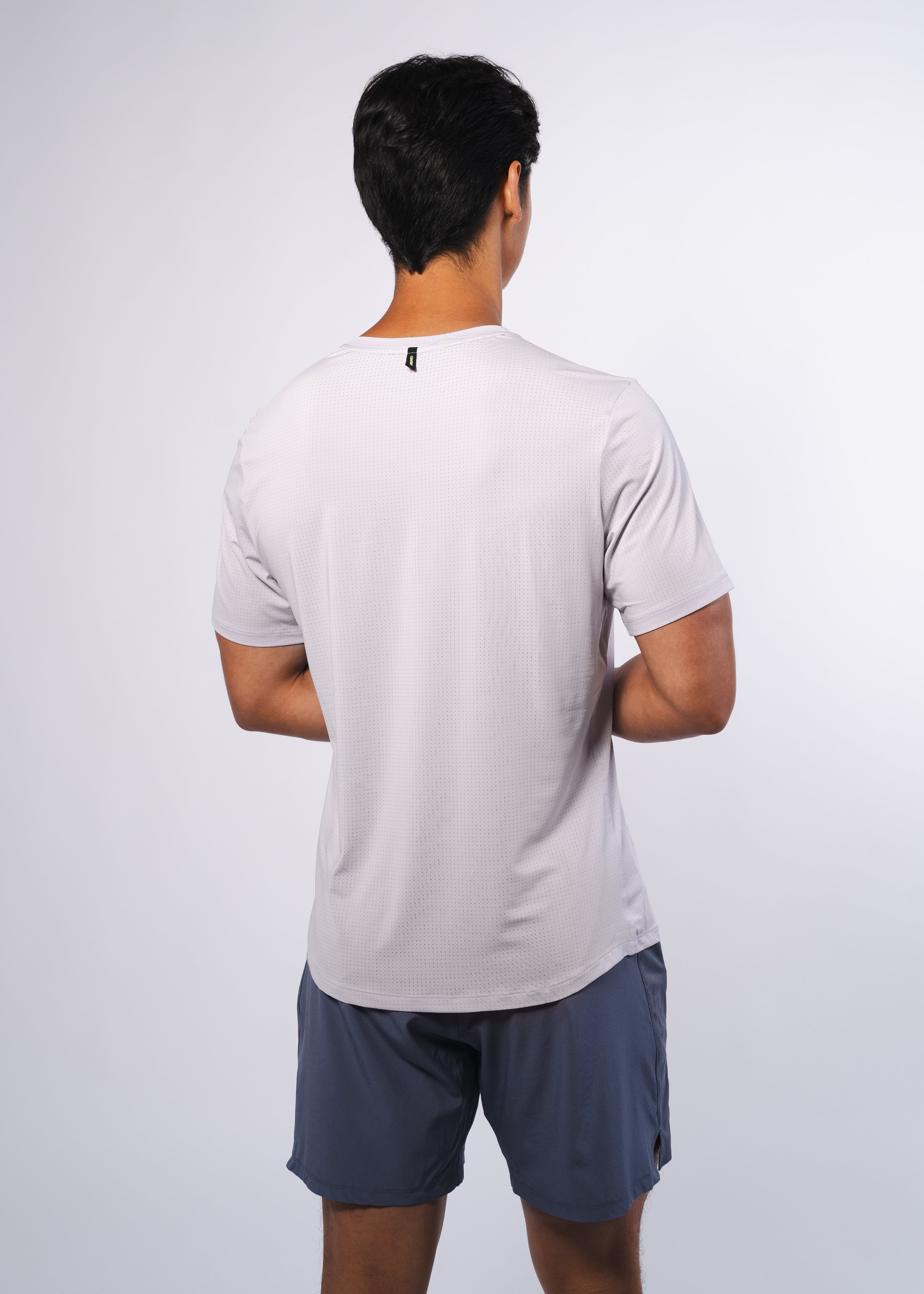 Back view of a man in a grey athletic shirt and blue-grey shorts.