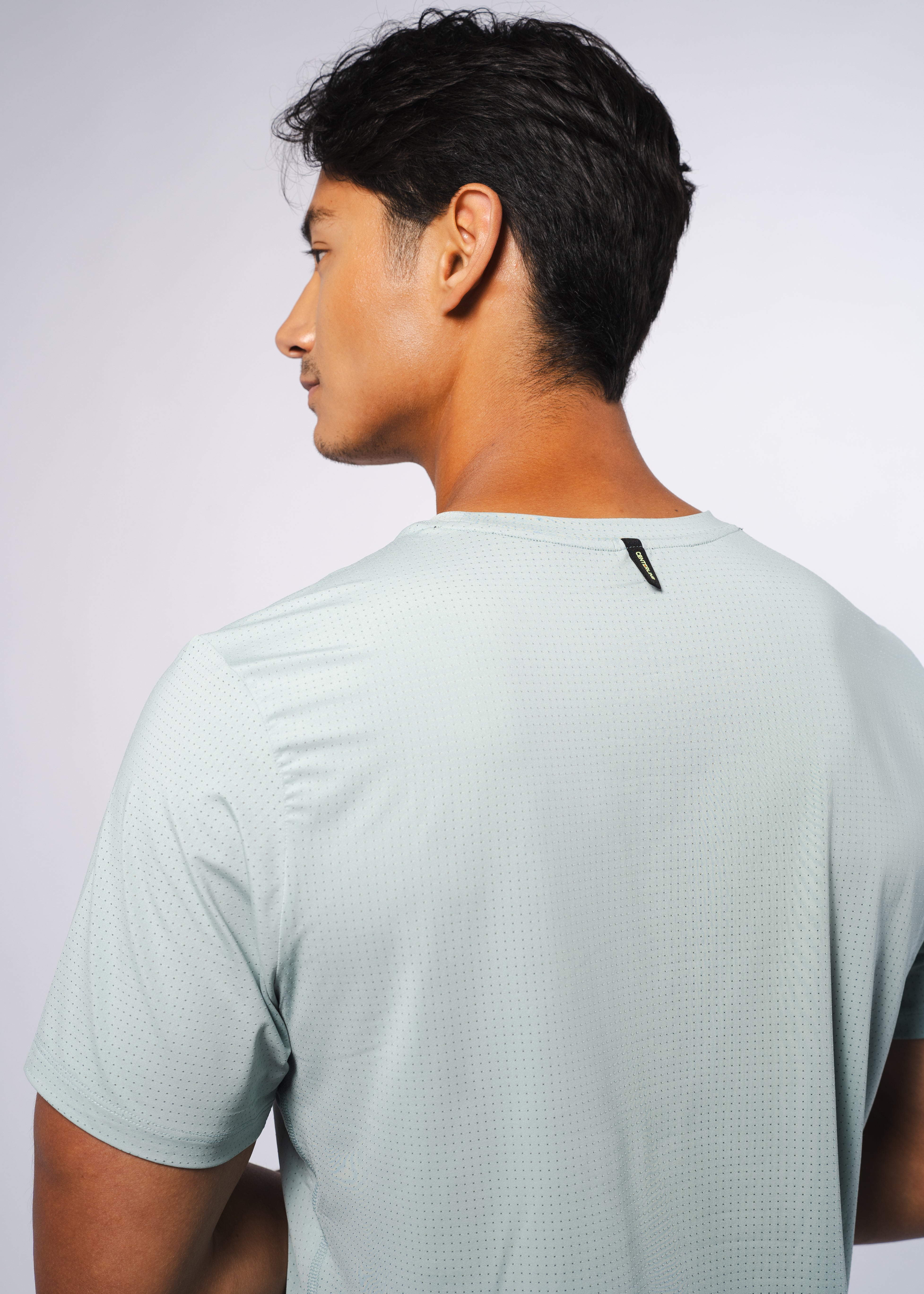 Back view of a man wearing a light blue perforated t-shirt.