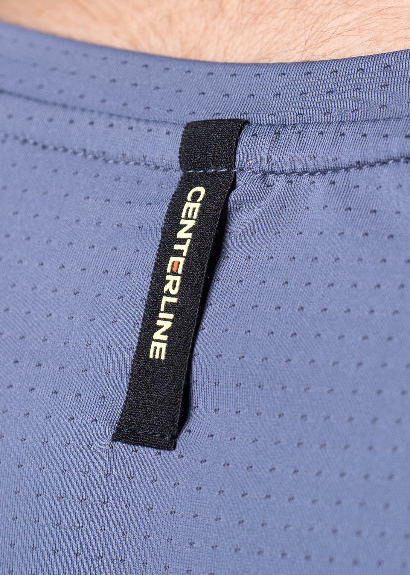 Close-up of a light blue, perforated athletic shirt with a black tag that reads "CENTERLINE" in yellow.