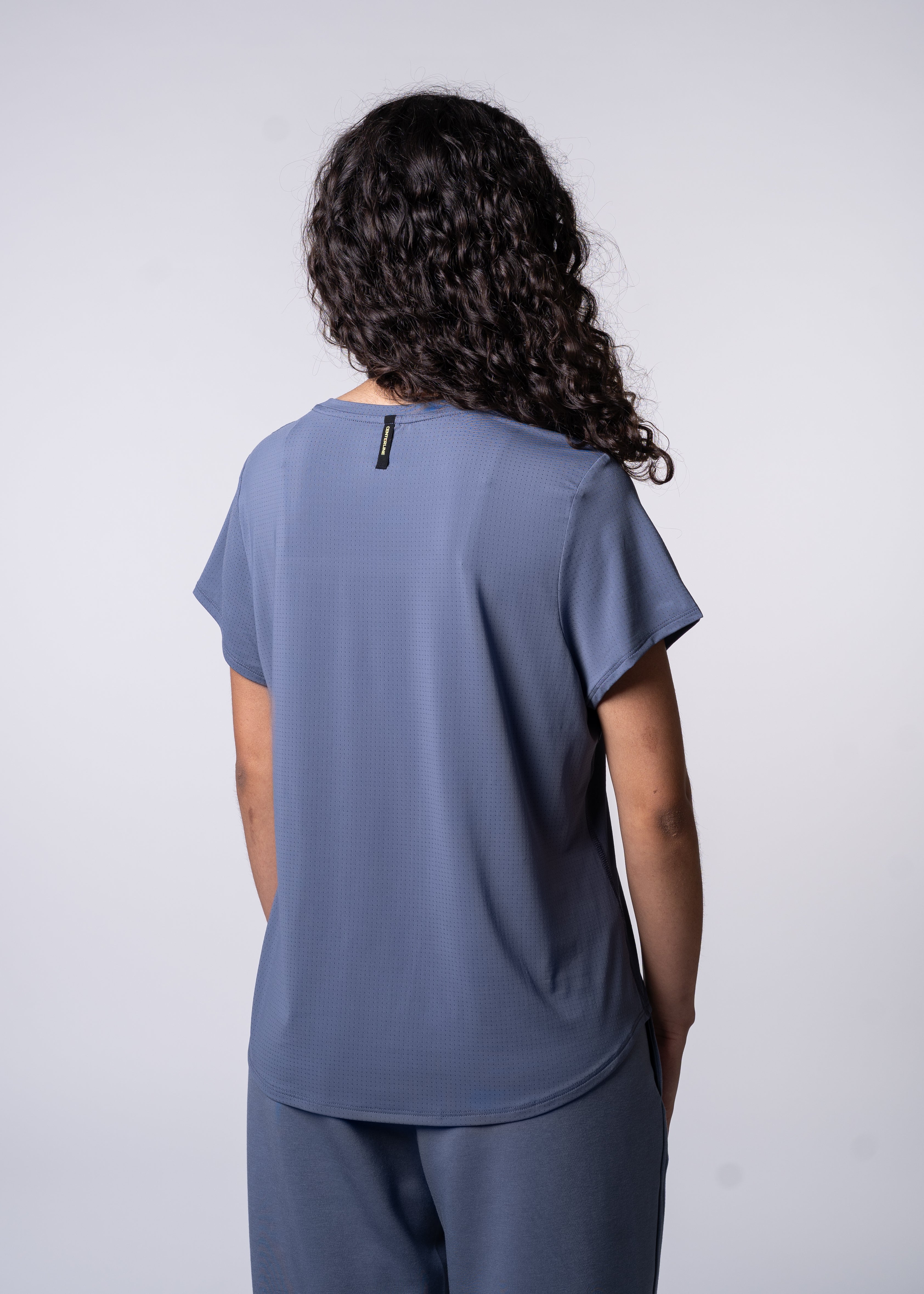 Back view of a person wearing a blue t-shirt and sweatpants.