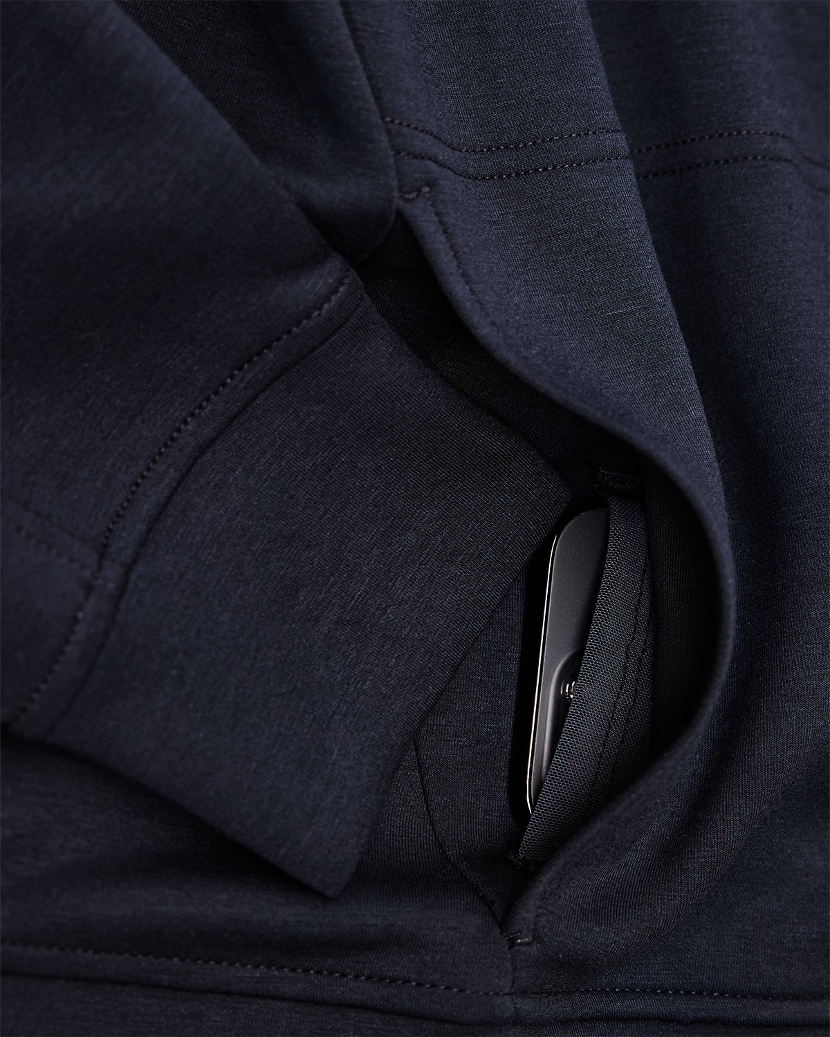 Close-up of a dark blue garment with a pocket, showing a metallic object inside.