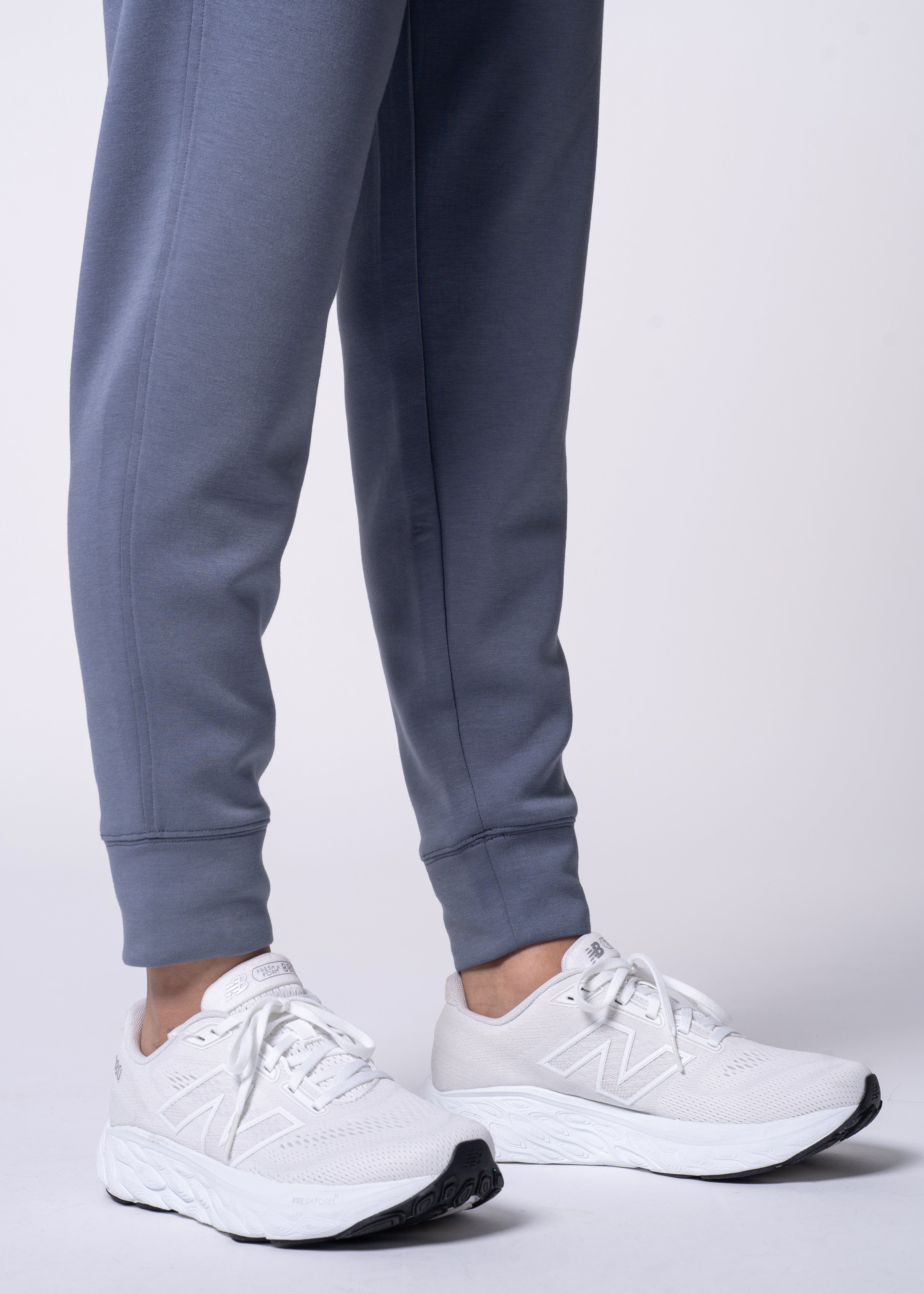 Person wearing blue sweatpants and white New Balance sneakers.