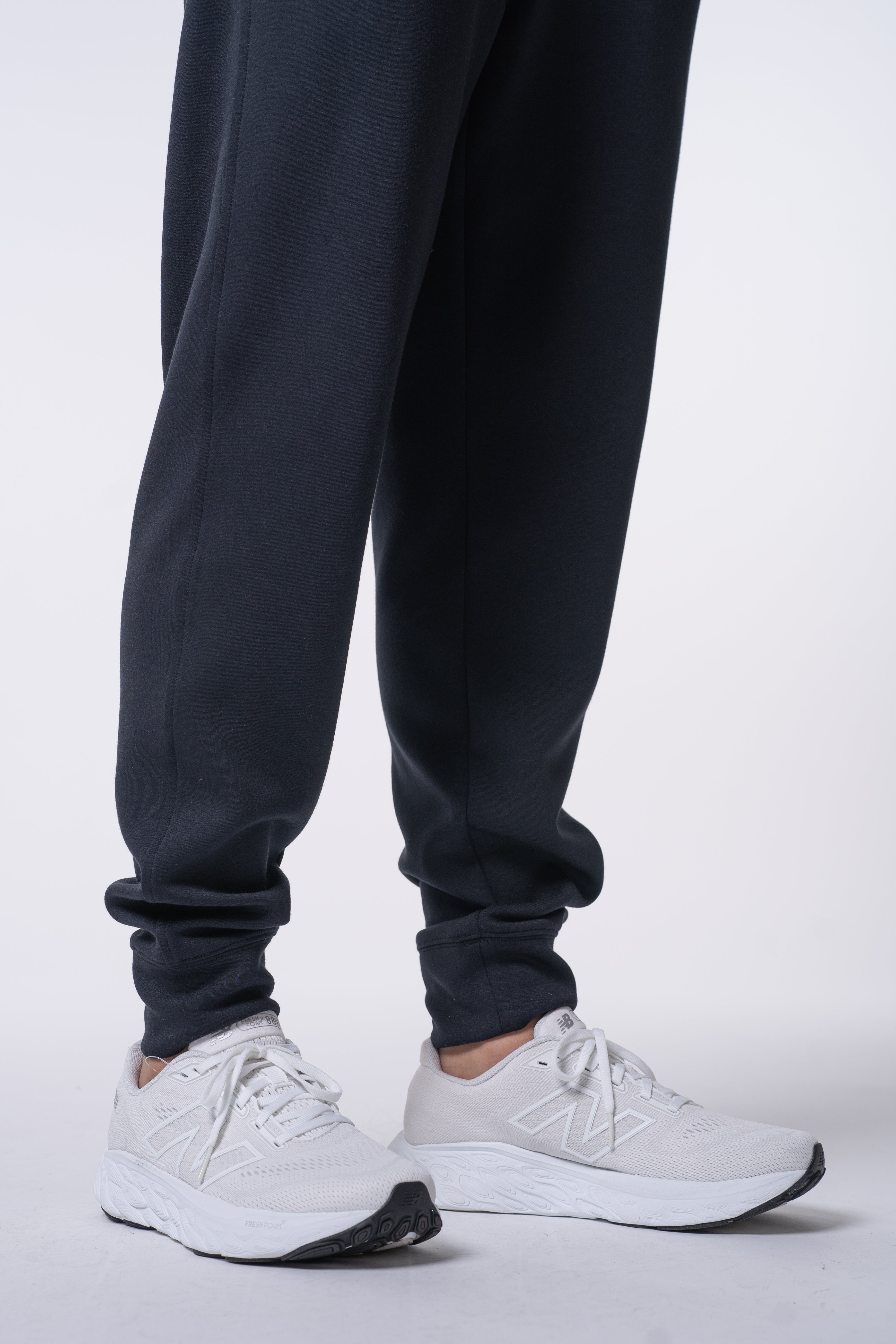 A person wearing dark blue sweatpants and white sneakers.