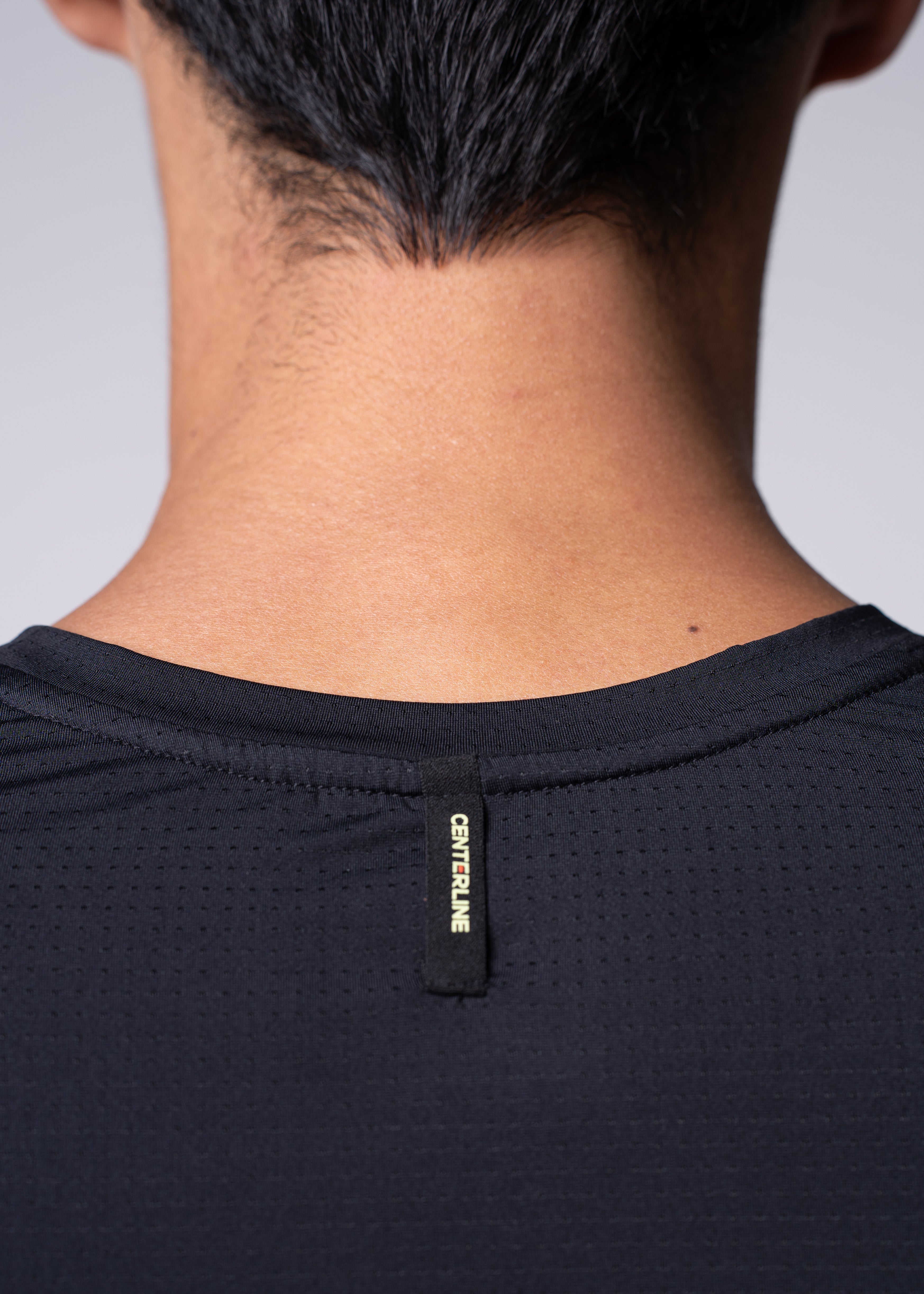 Close-up of a person's neck and shoulders wearing a black athletic shirt with "CENTERLINE" label.