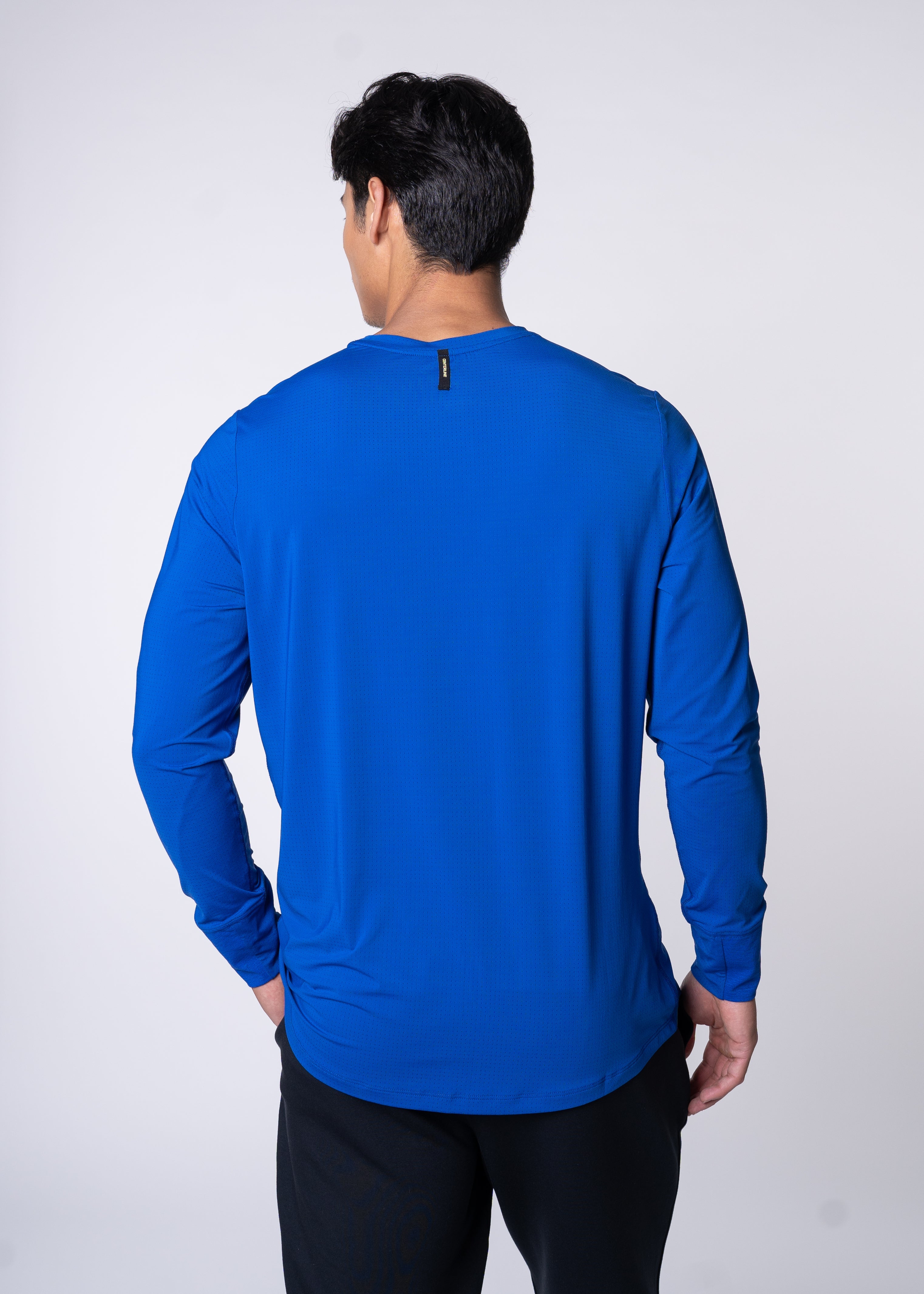 Man from behind wearing a blue long-sleeve shirt and black pants.