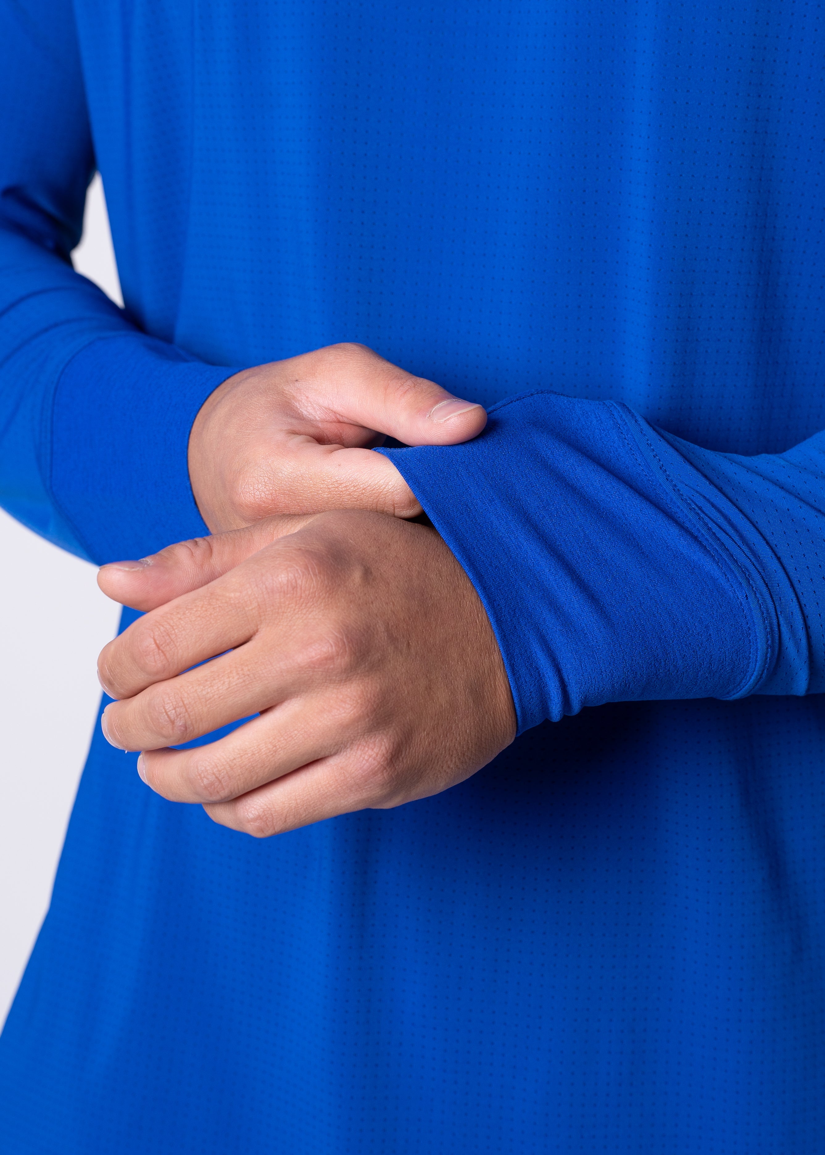 Close-up of a person in a blue long-sleeve shirt with thumb holes in the sleeves.