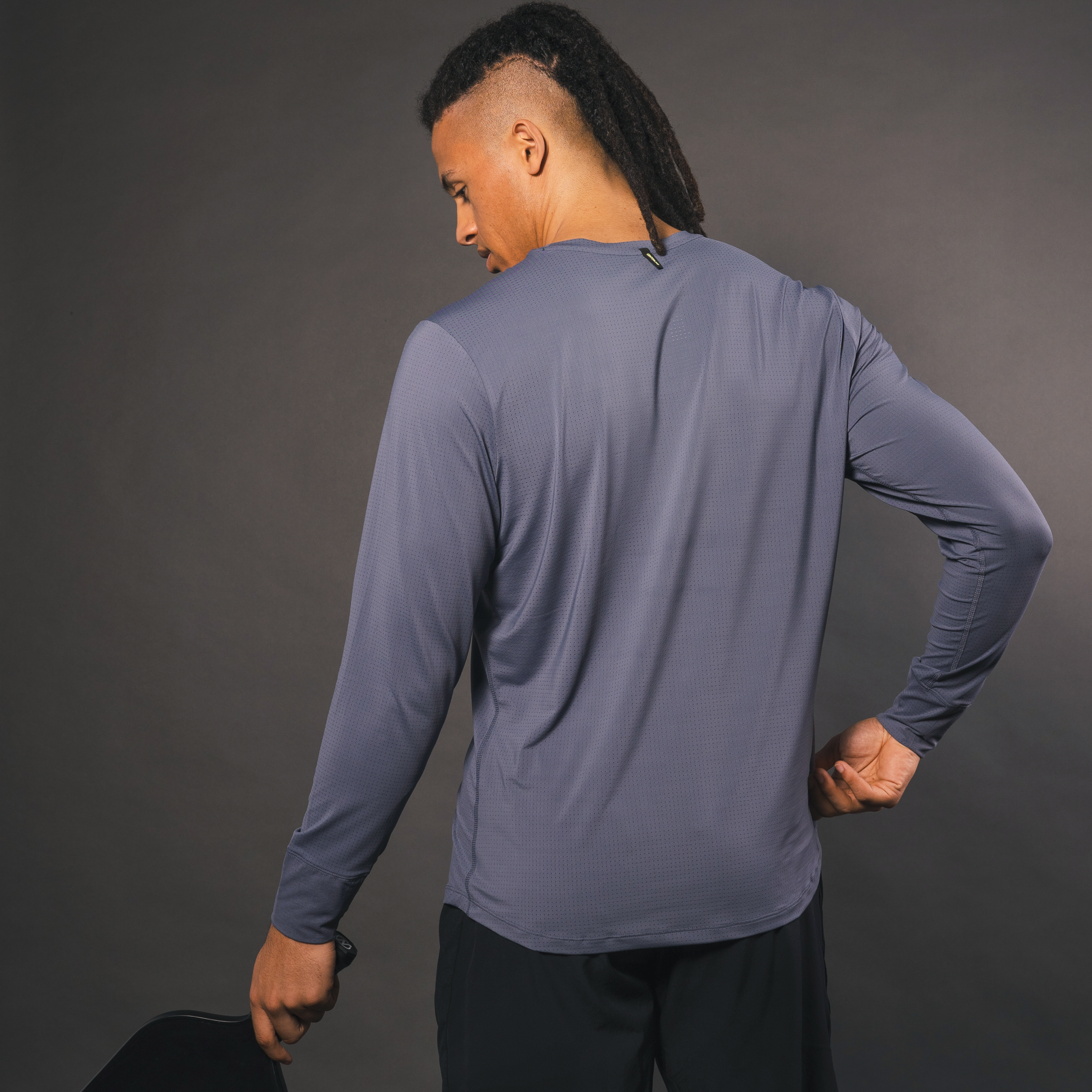 Man in gray long-sleeved shirt and black shorts, back view.