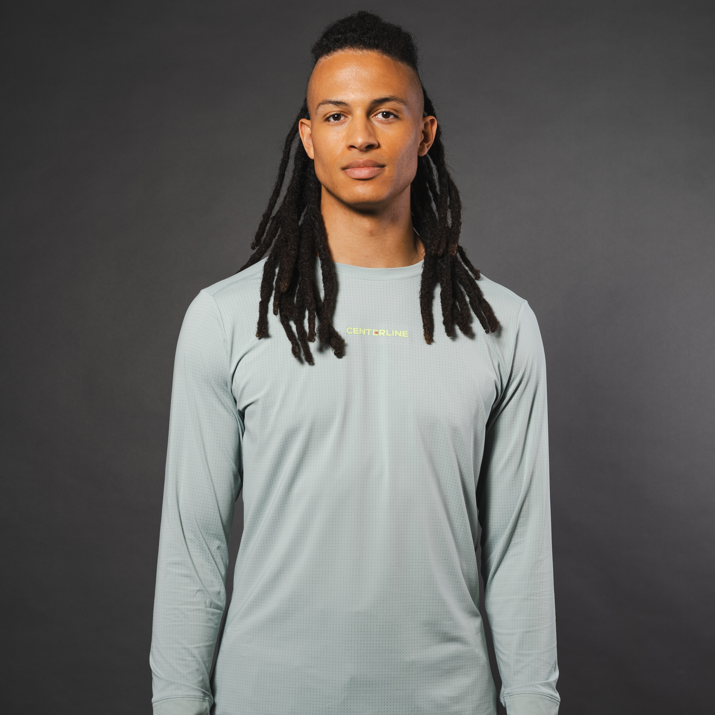 Man in gray long sleeve shirt with "CENTERLINE" logo, dark gray background.