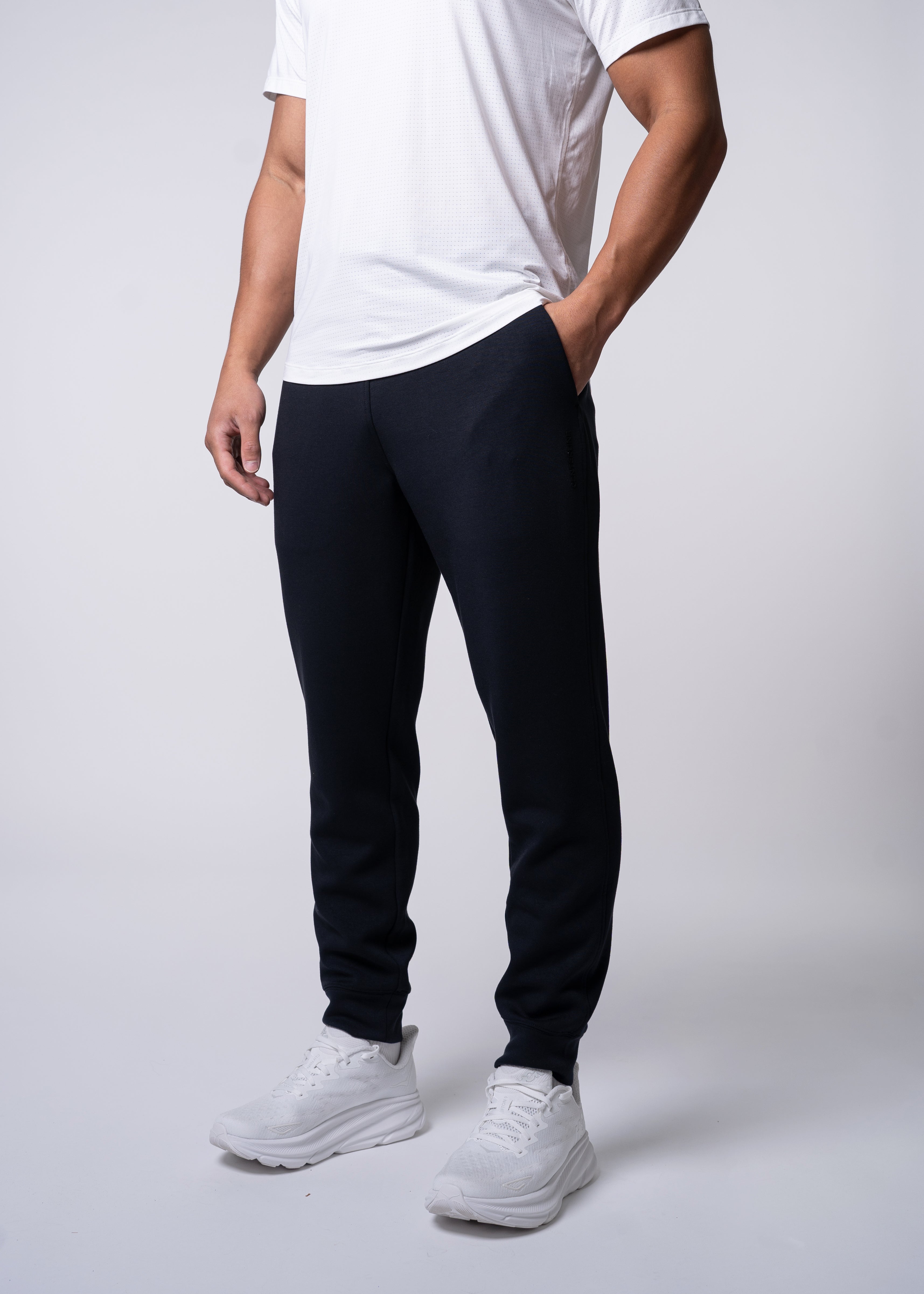 Man in white shirt and black pants with white sneakers.
