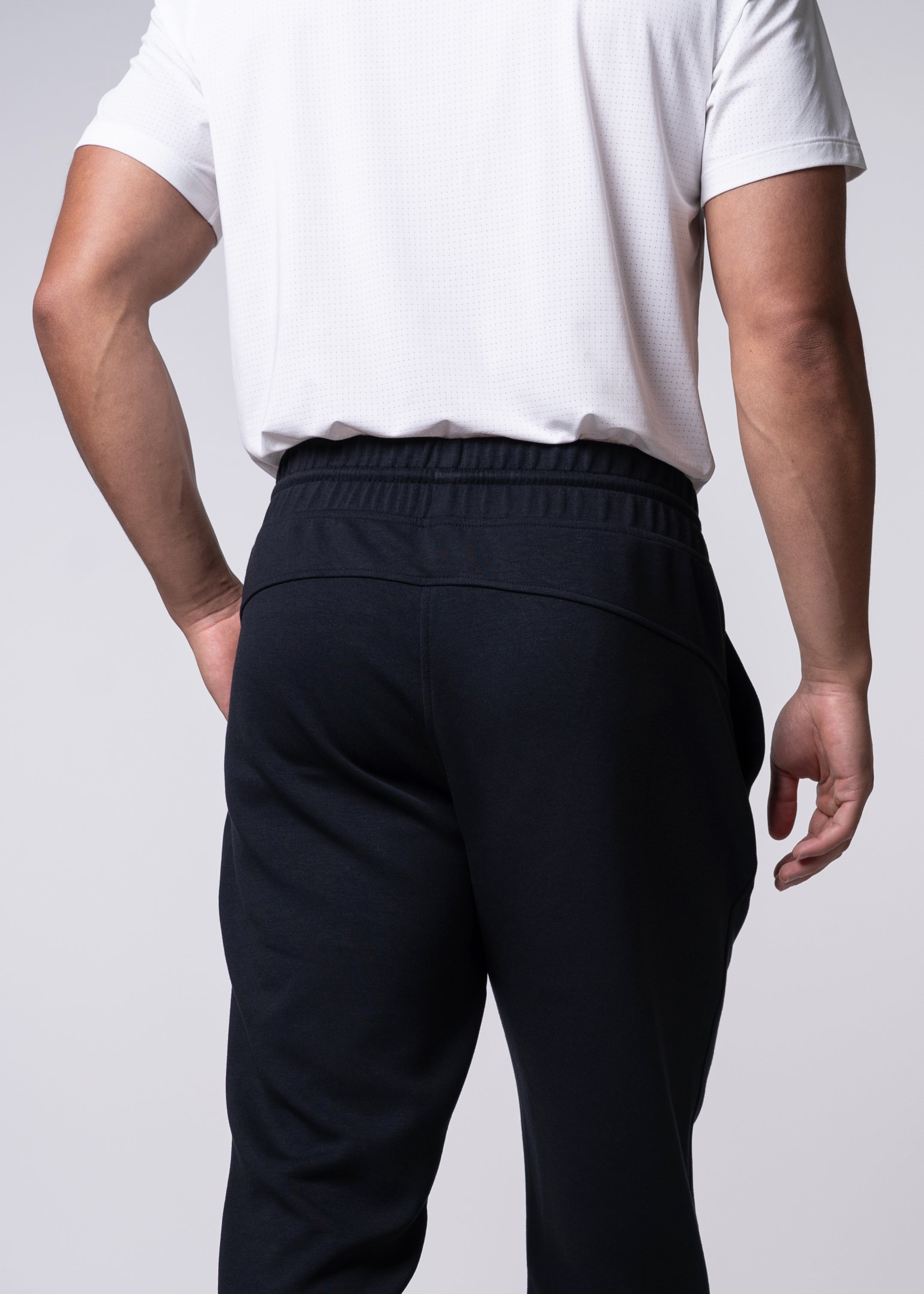 Person wearing a white shirt and navy sweatpants.