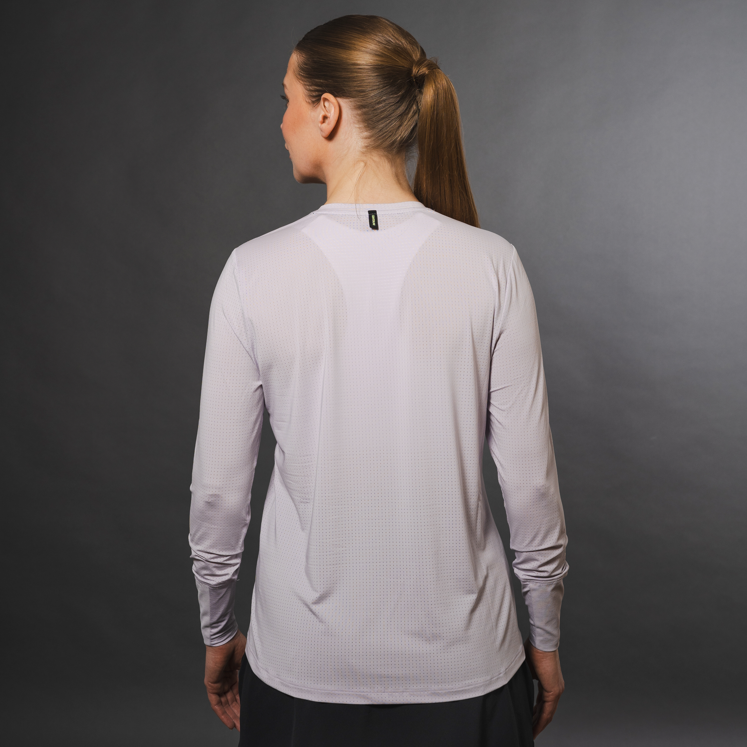 Woman facing away wearing long-sleeved, gray, athletic shirt, hair in a ponytail.