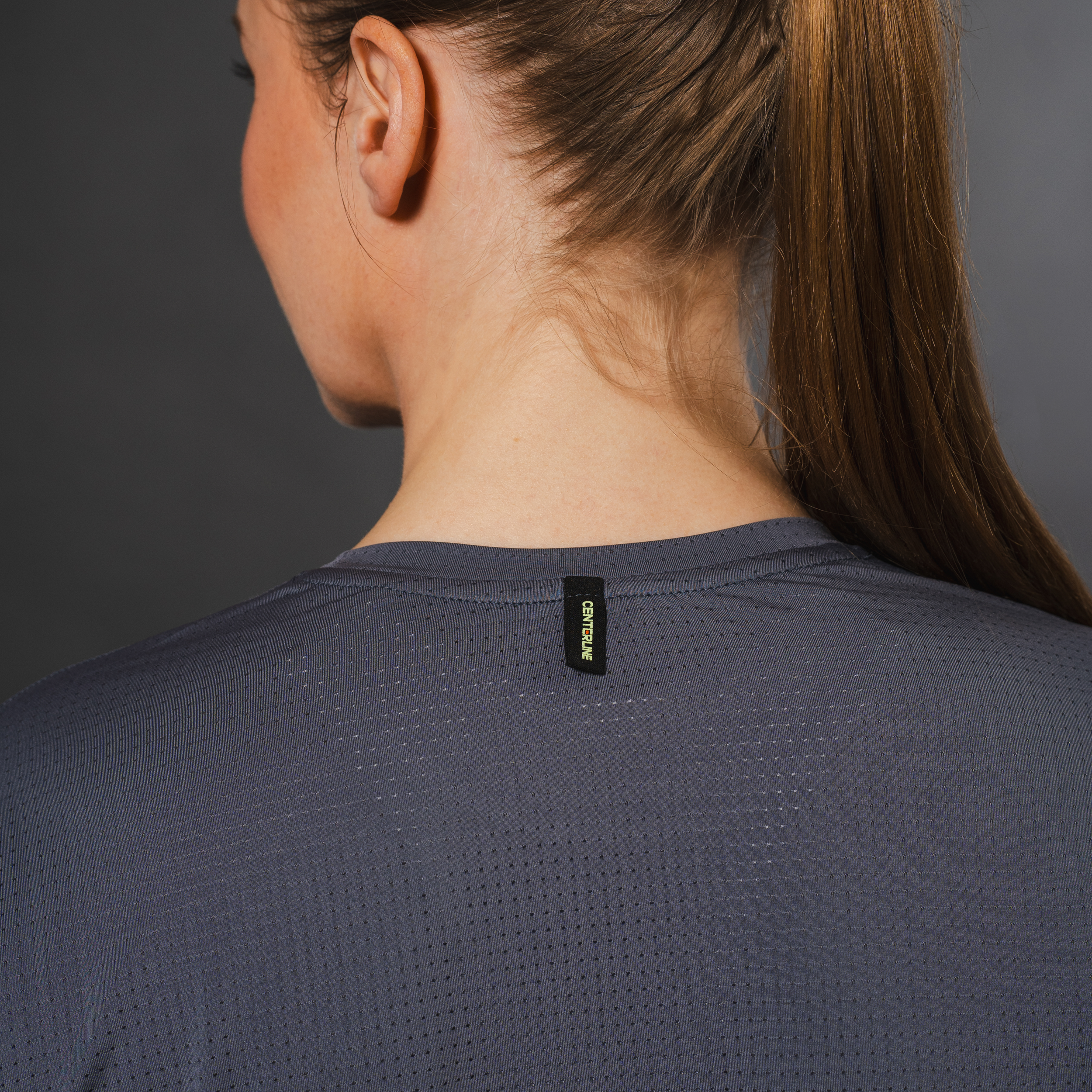 Woman wearing a gray mesh shirt, back view.