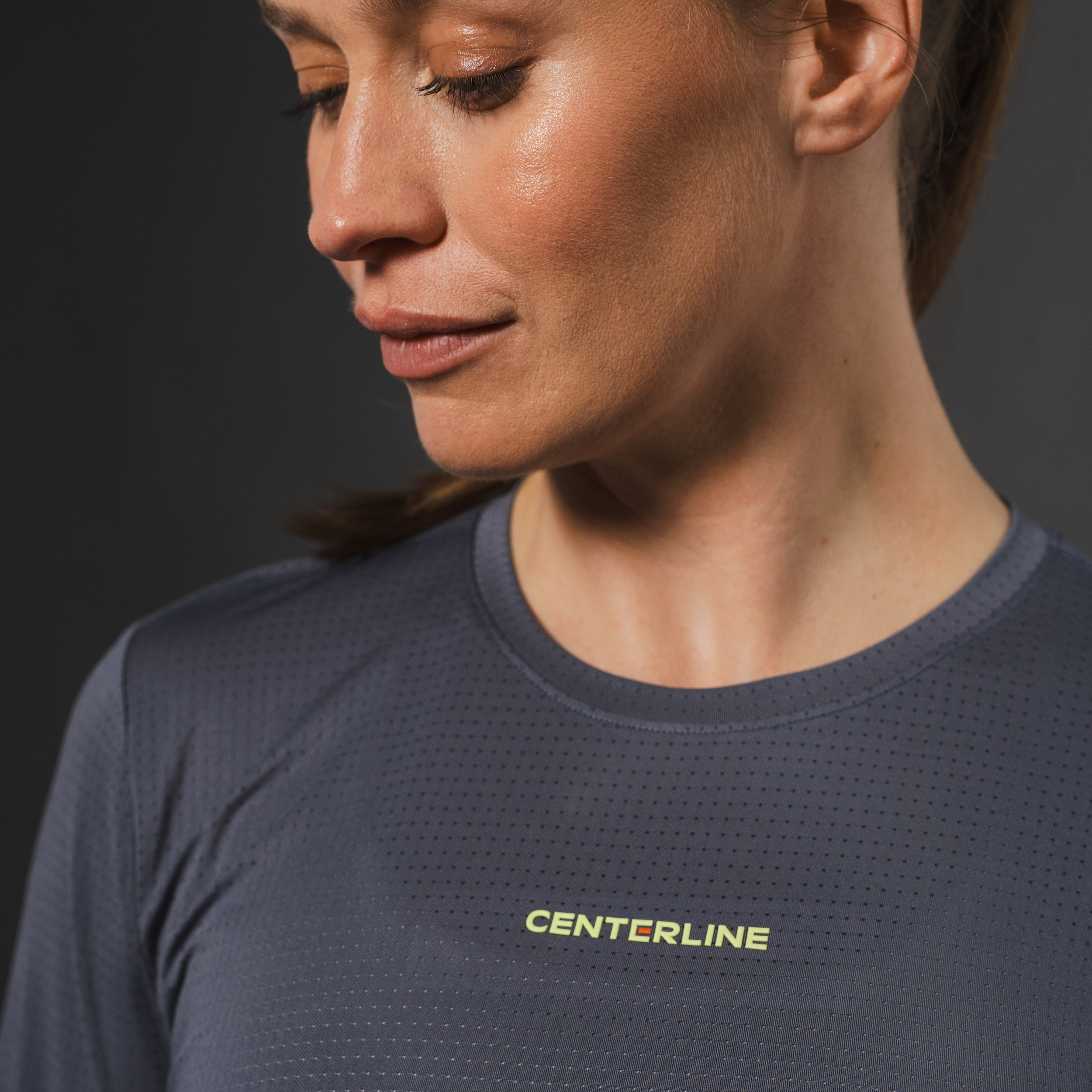 Woman in grey athletic shirt with "CENTERLINE" logo.