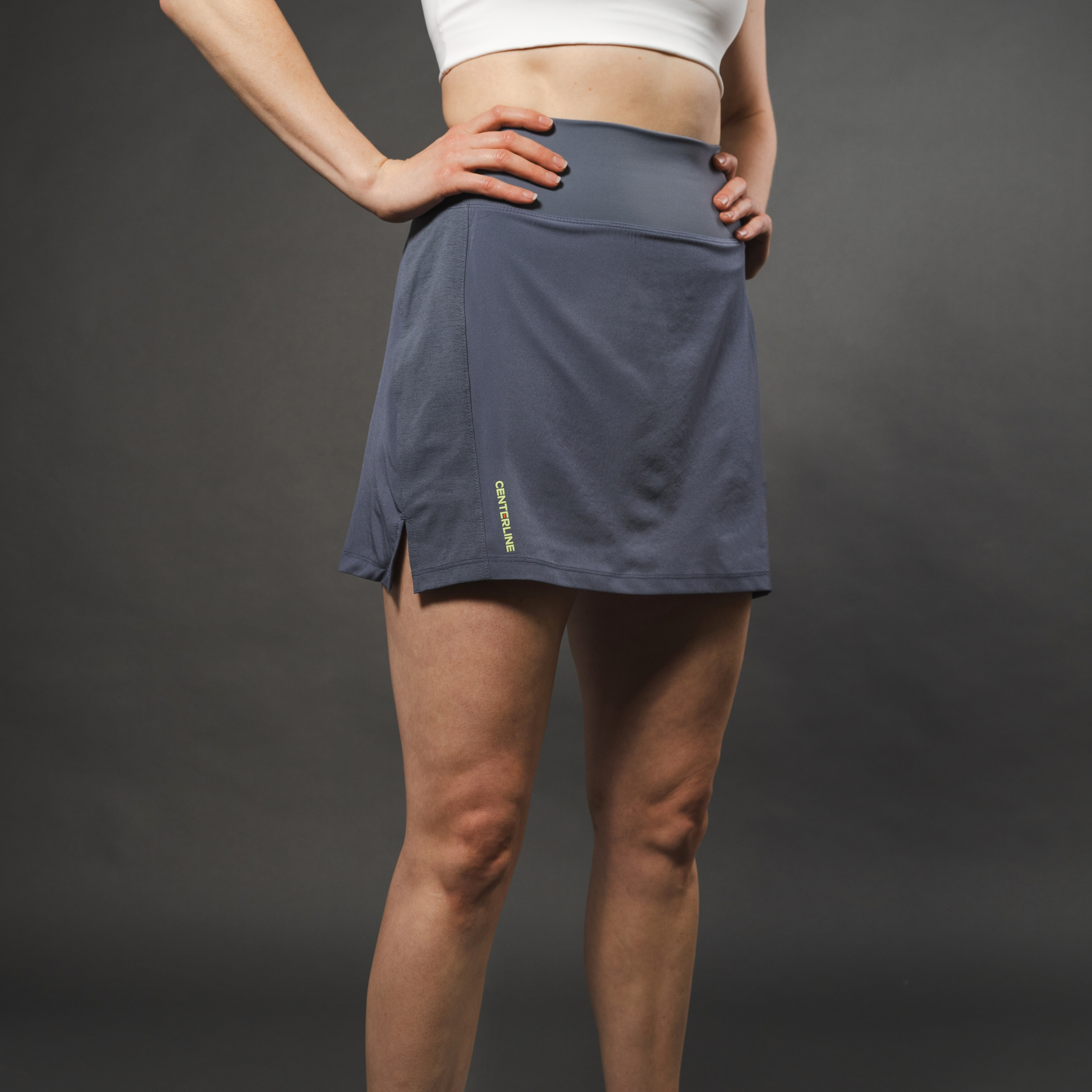 Woman in grey athletic skort with white top, hands on hips.