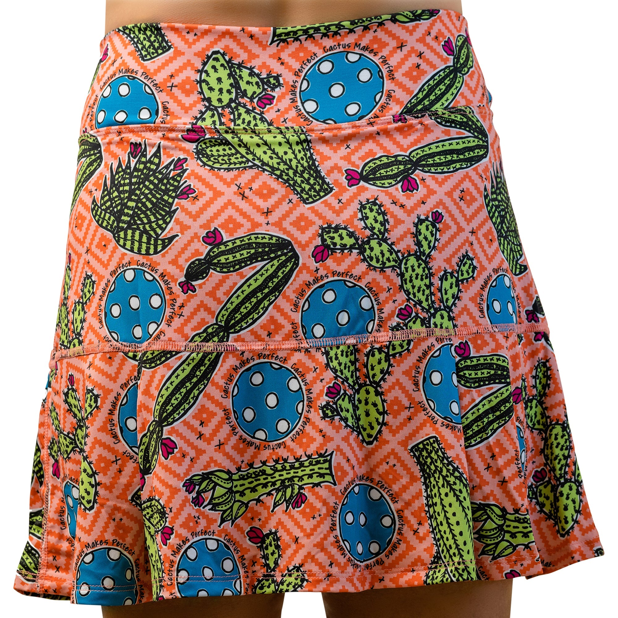 Orange cactus pattern pleat skort by Pickleball Bella, featuring green cacti, pink flowers, blue polka dot circles, and 'Cactus Makes Perfect' text.