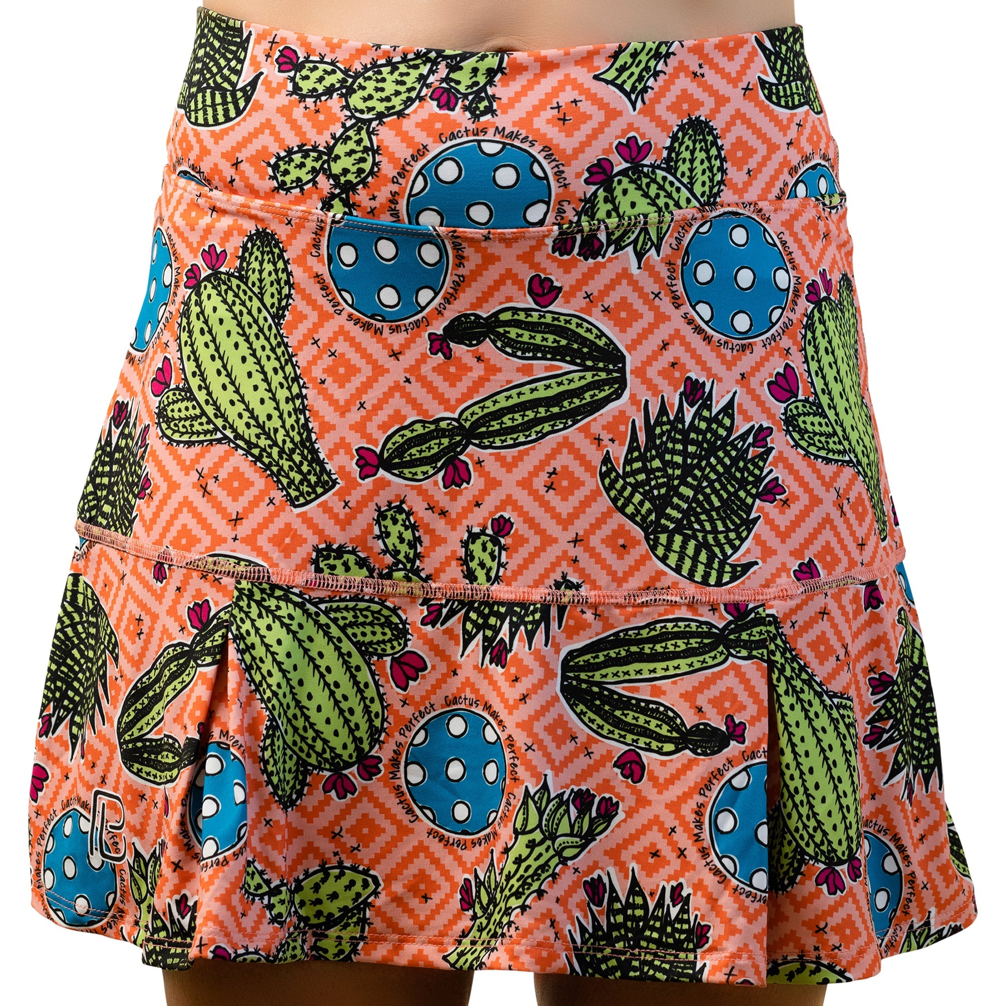 Orange pleat skort with a cactus pattern by Pickleball Bella, featuring green cacti, pink flowers, and blue pickleballs with 'Cactus Makes Perfect' text.