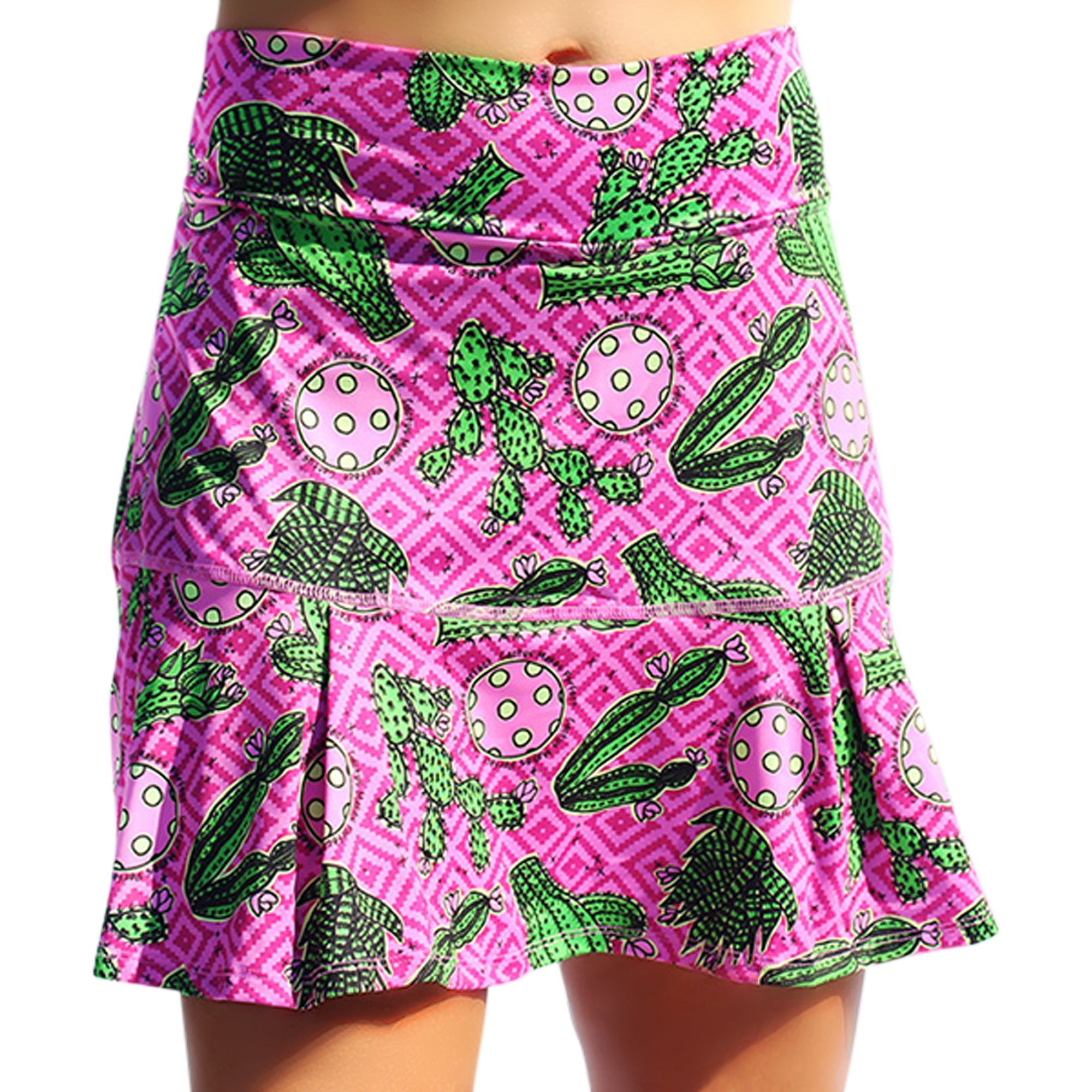 Pink drop pleat skort by Pickleball Bella with green cactus and pink polka dot pattern on a geometric background.